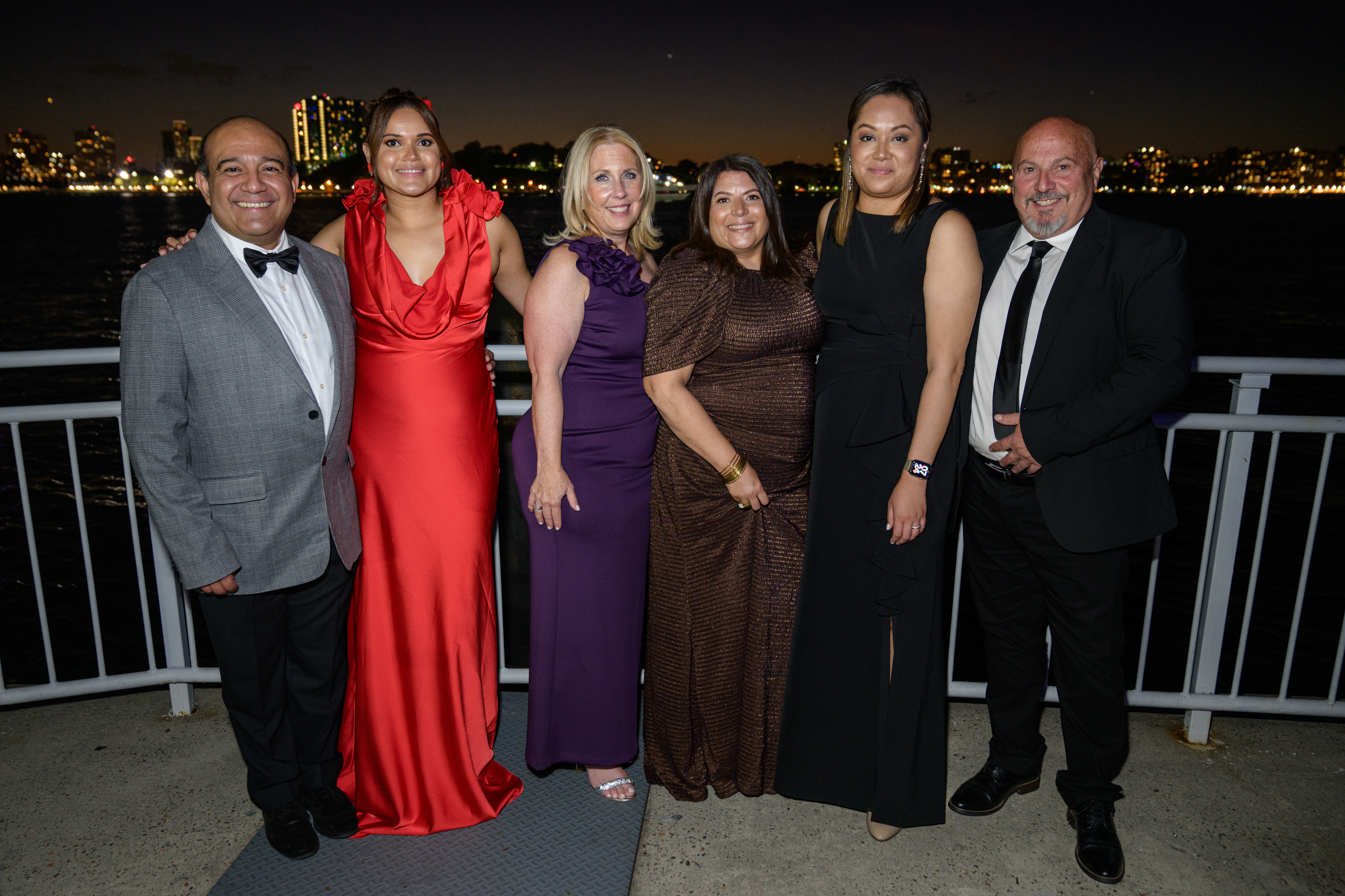 Members of the Stevens community gather for a picture on the water at the Stevens Awards Gala, with the Stevens campus in the background