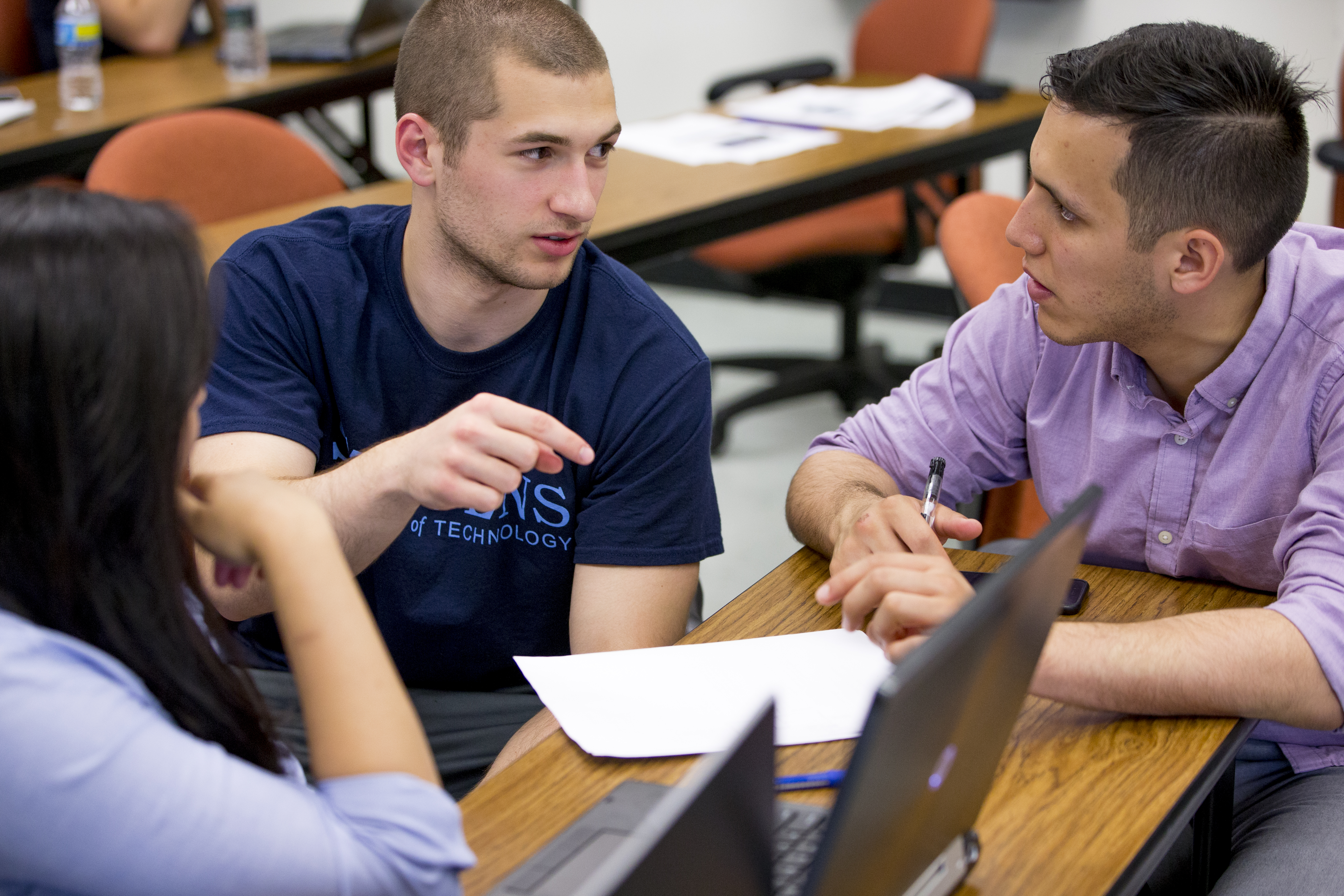 Three graduate systems engineering students work together at a table during class.
