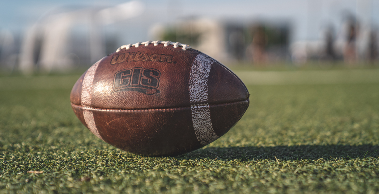 A Wilson football placed on a football field.
