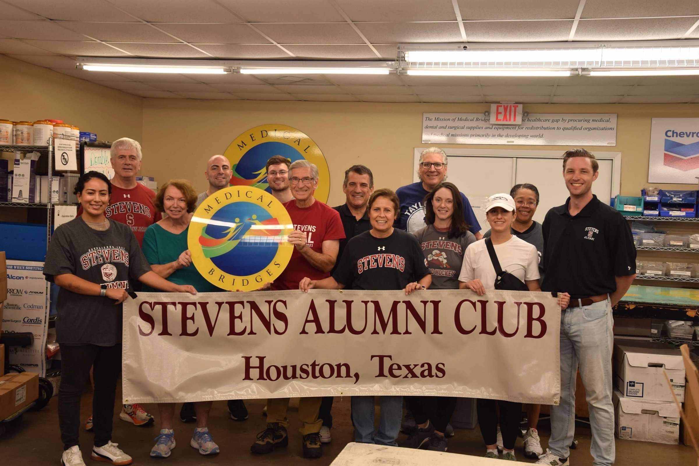 Members of the Houston Regional Network gather for a volunteering event and pose with the Stevens Alumni Club banner