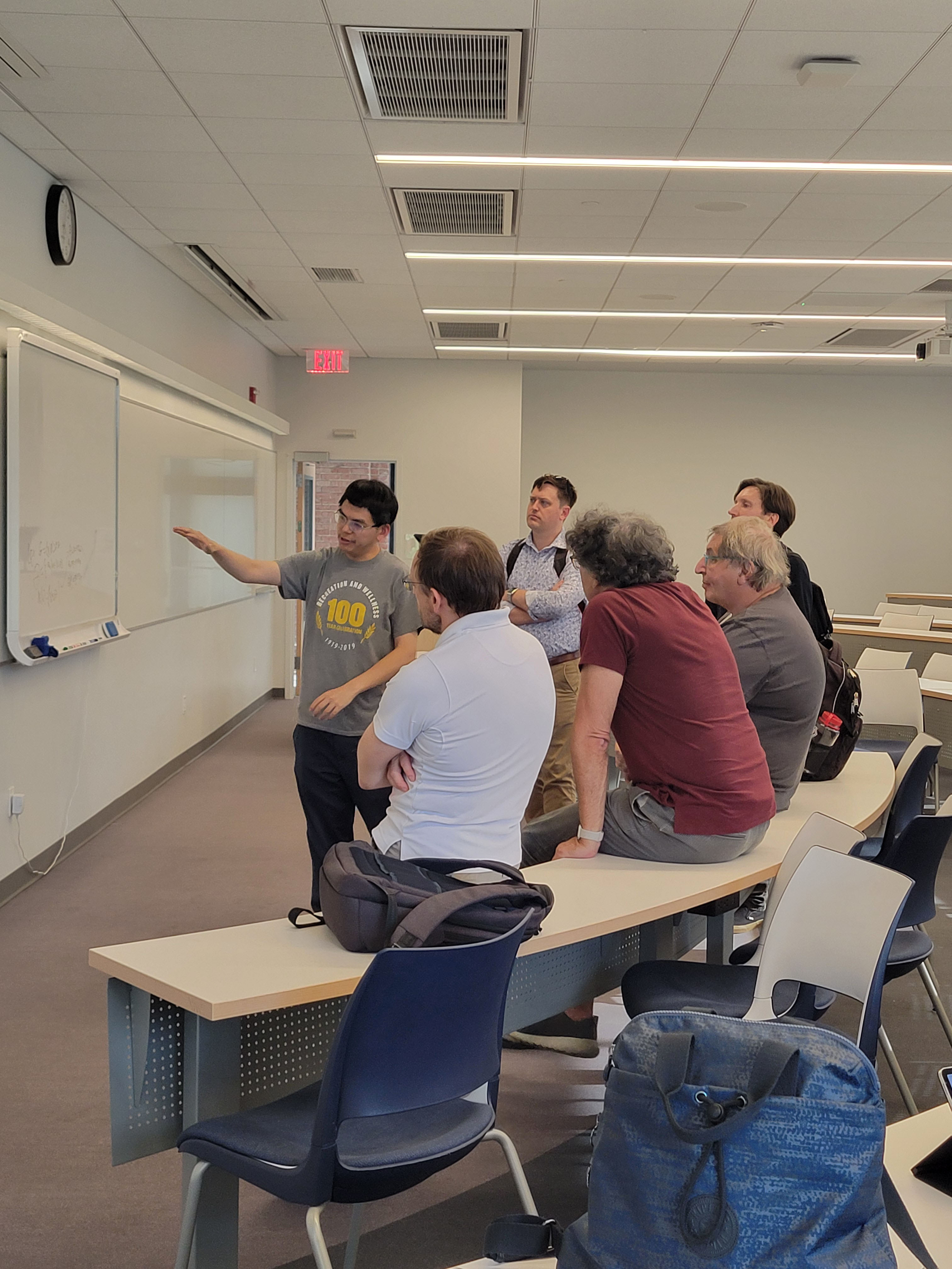 Six math educators look at a problem on a white board during a mathematics conference at Stevens.