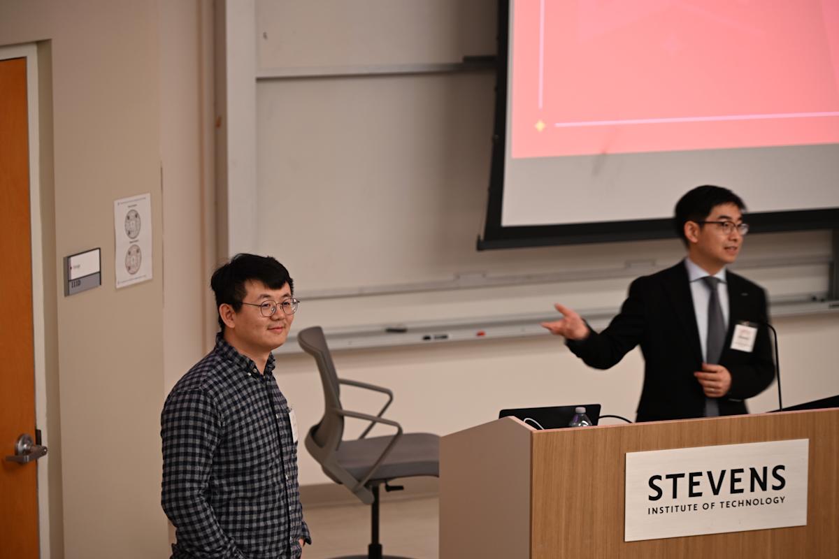 A photo of a person in a suit behind a podium introducing another person to his right.