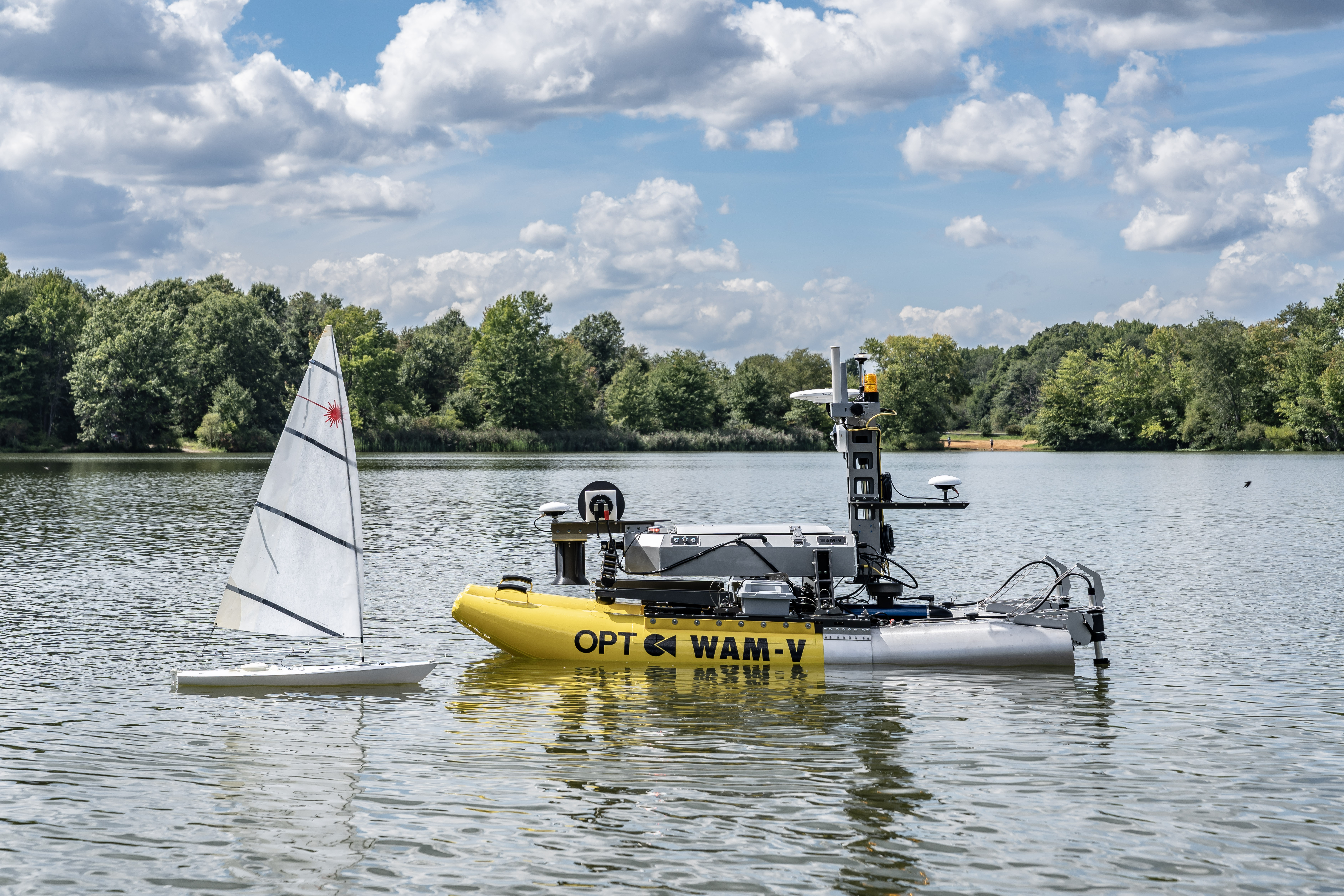 A photograph of the WAM-V 8 and a sailboat sitting on the water. 