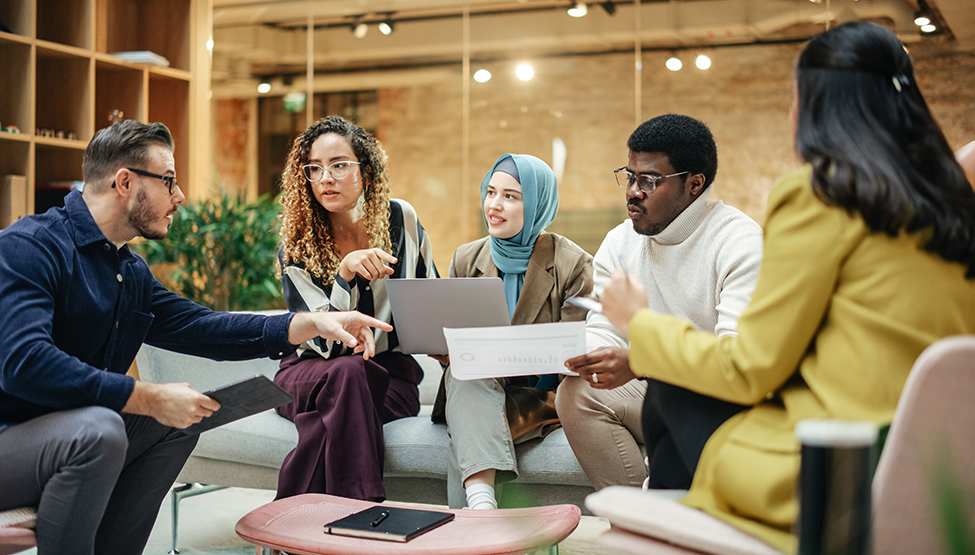Group of diverse workers sit together discussing ideas