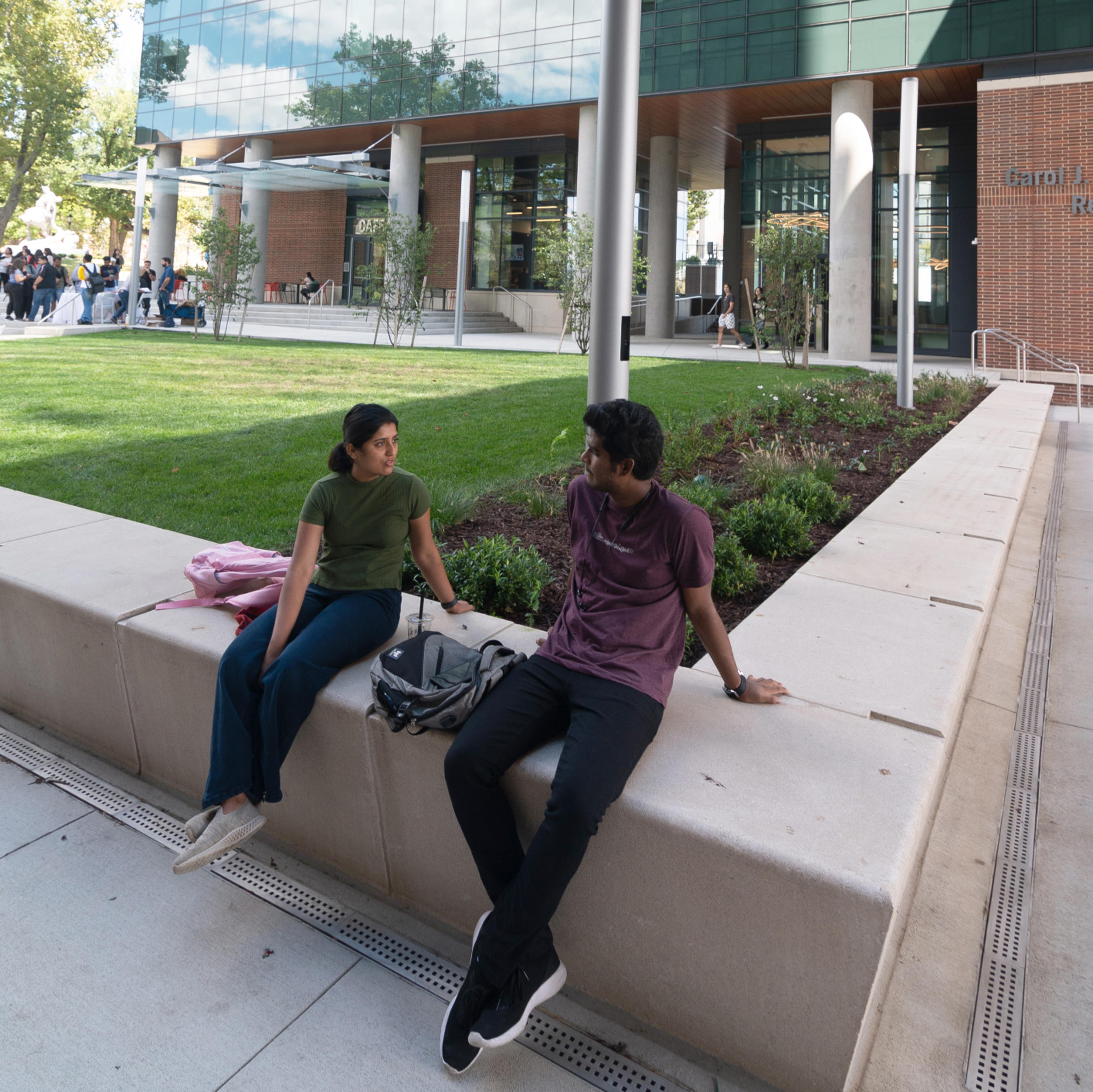 Students converse outside the UCC next to grass.
