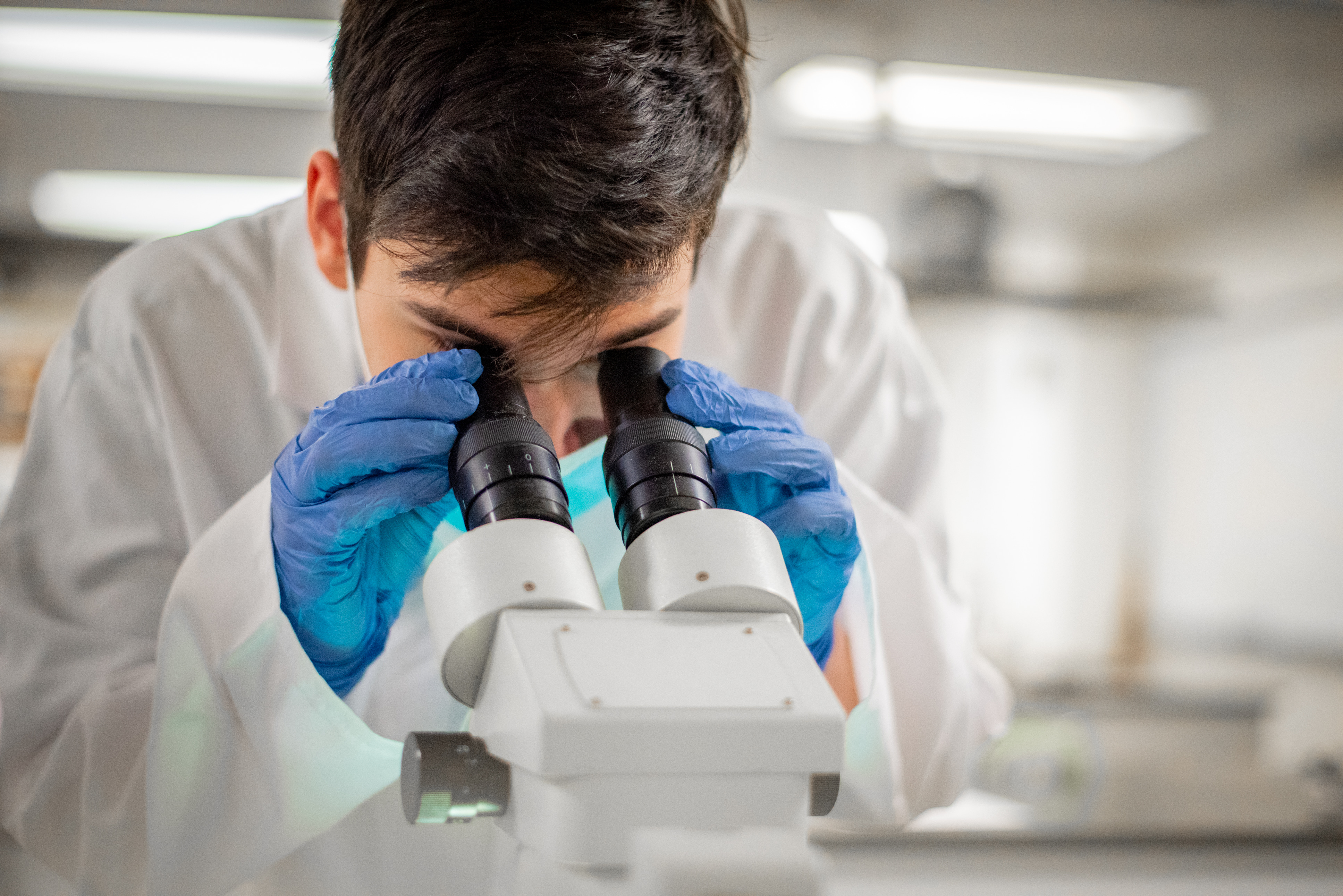 Student in lab looking through microscope