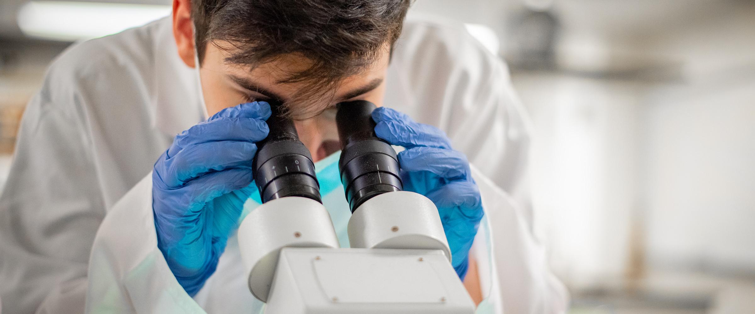 Student in lab looking through microscope