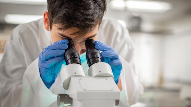Student in lab looking through microscope