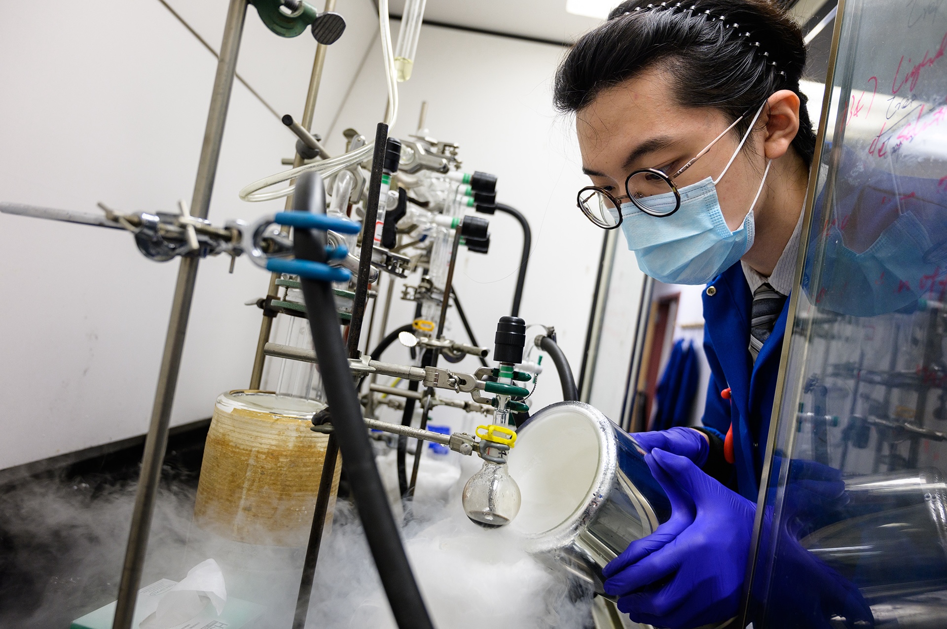 A female student wearing a mask pouring chemicals in a laboratory