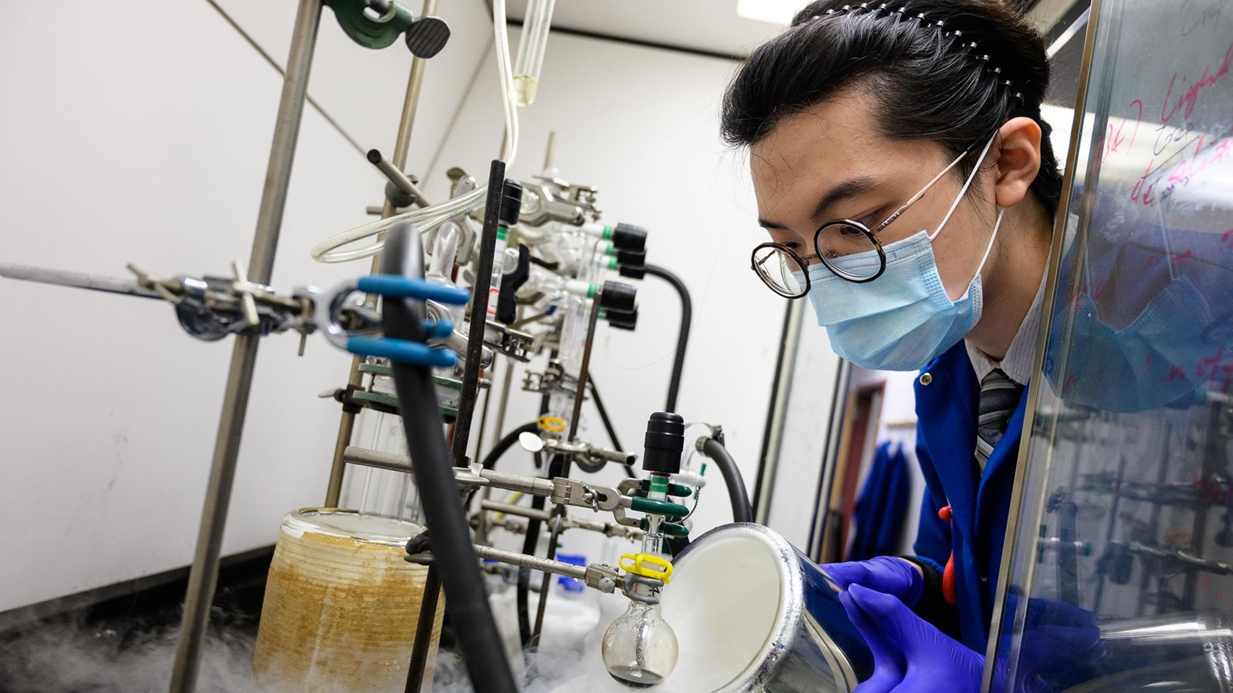 A female student wearing a mask pouring chemicals in a laboratory
