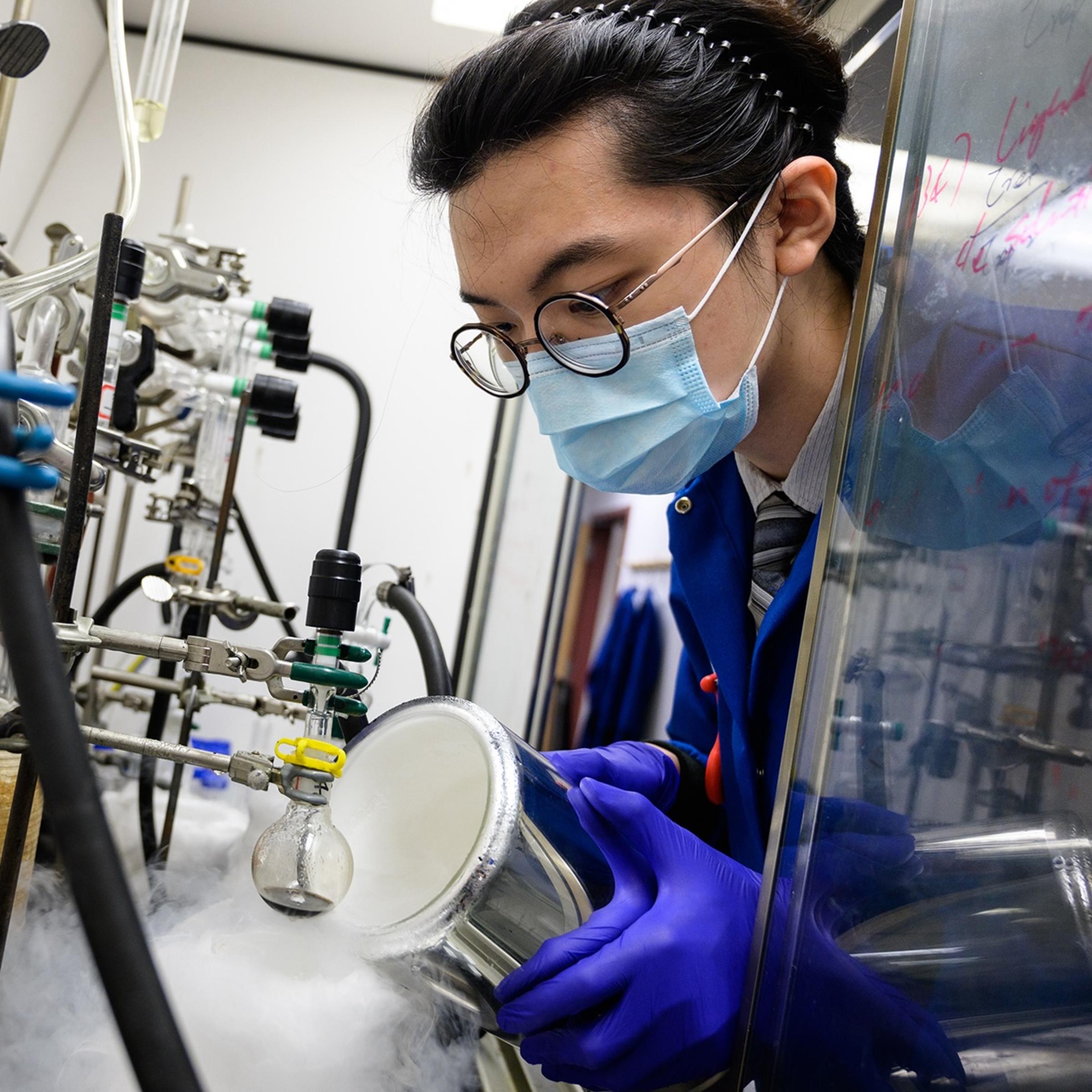 A female student wearing a mask pouring chemicals in a laboratory