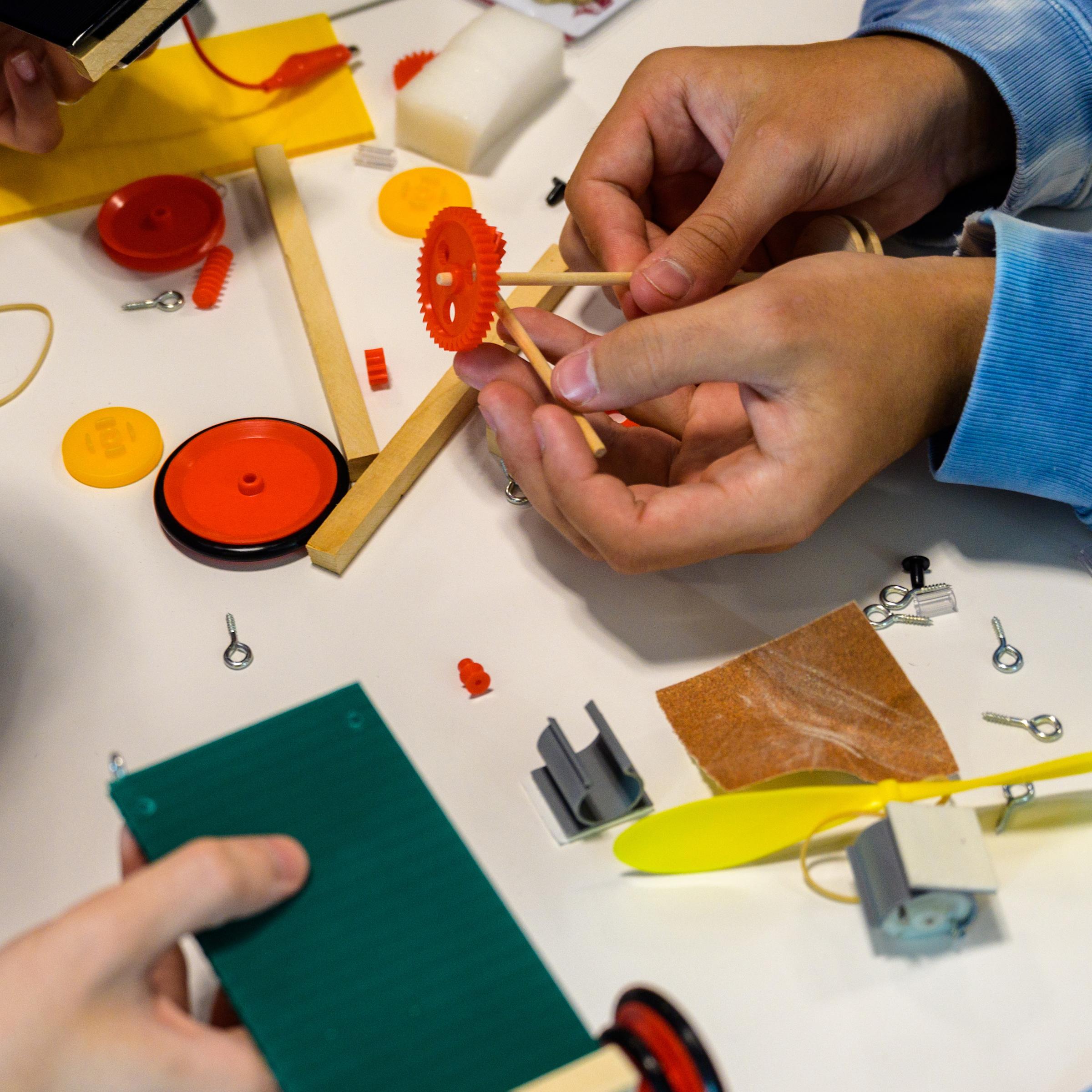 Two pre-college students' hands working on the table with building materials