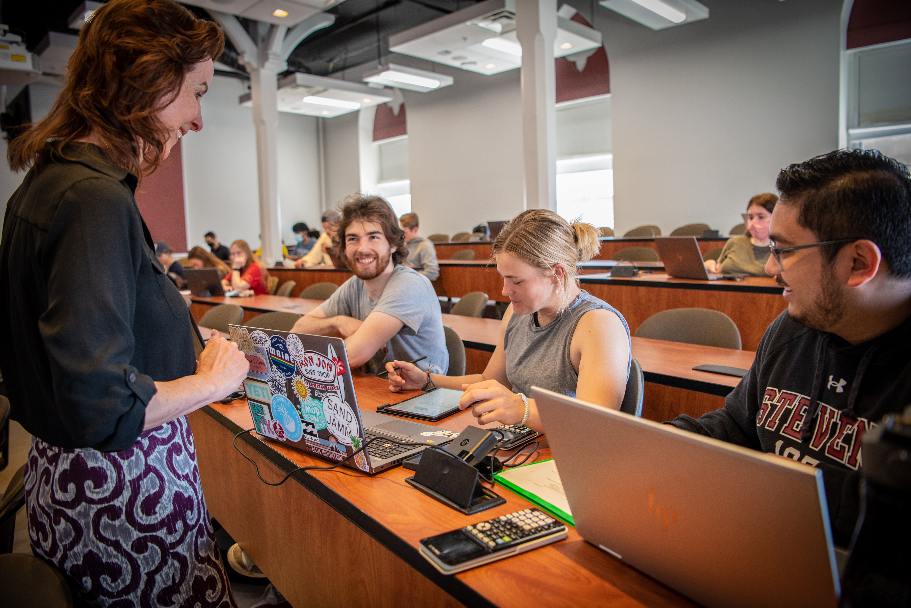 Three students smile at professor