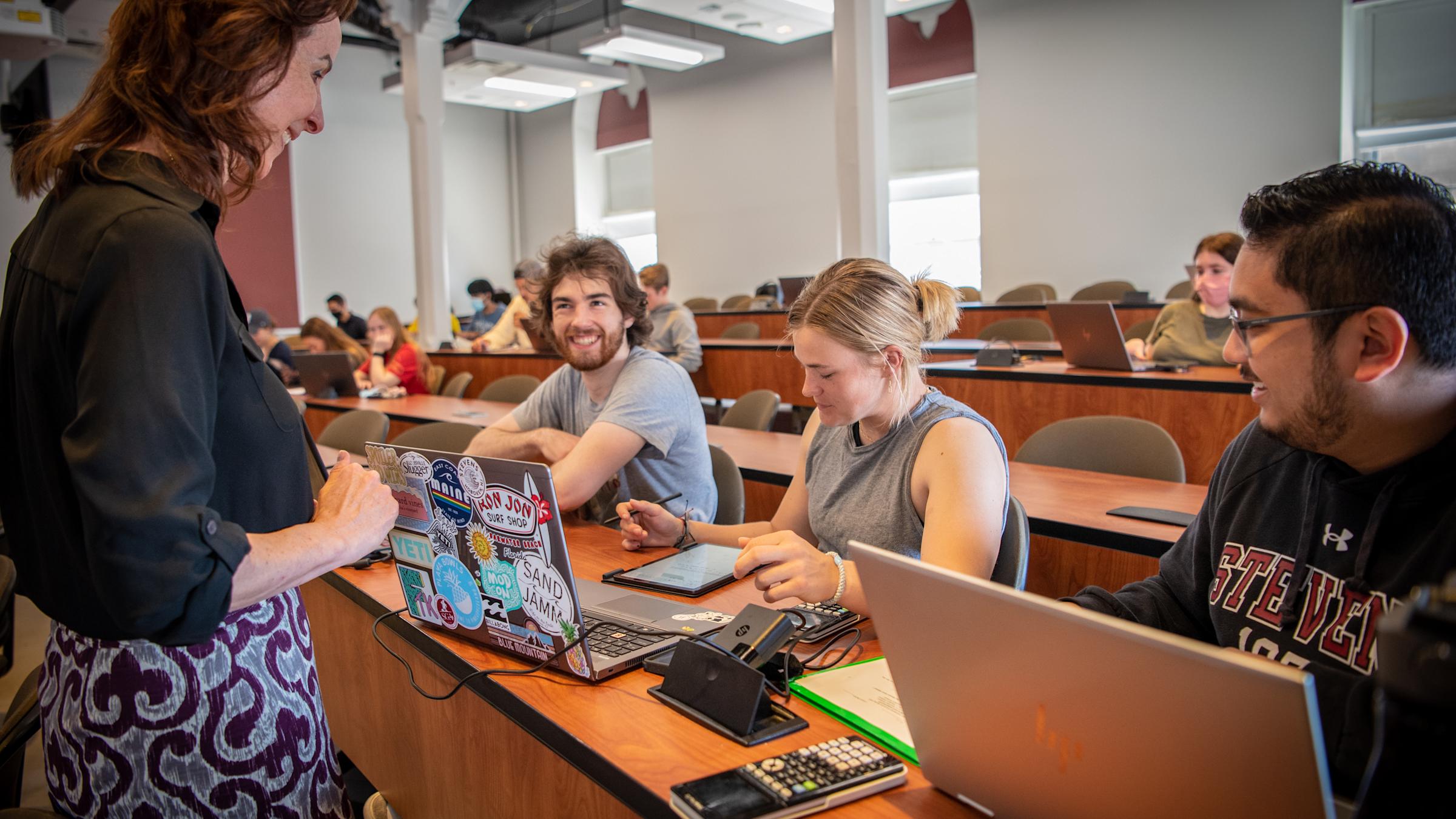 Three students smile at professor