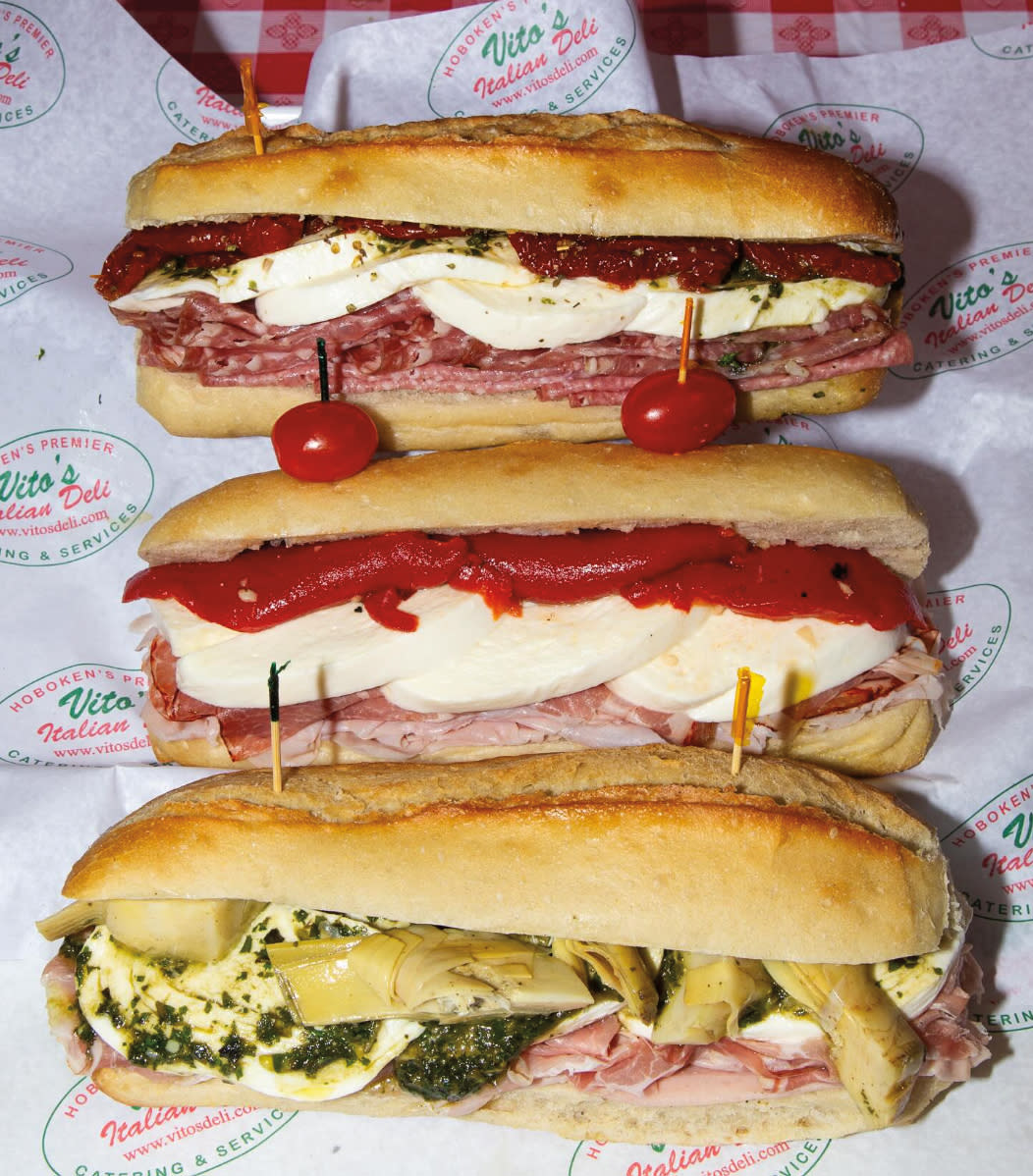 3 sub sandwiches, filled with meat, mozzarella cheese, red peppers, pesto and artichokes.