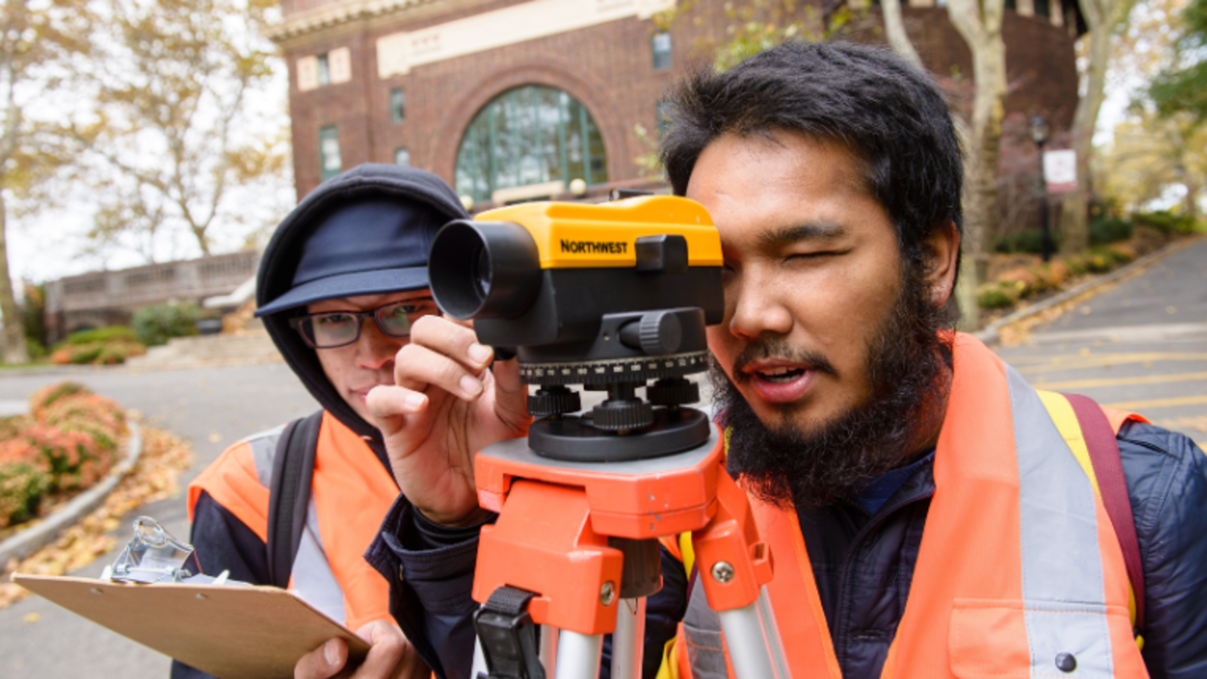 Two civil engineering students use a surveying tool on the Stevens campus.