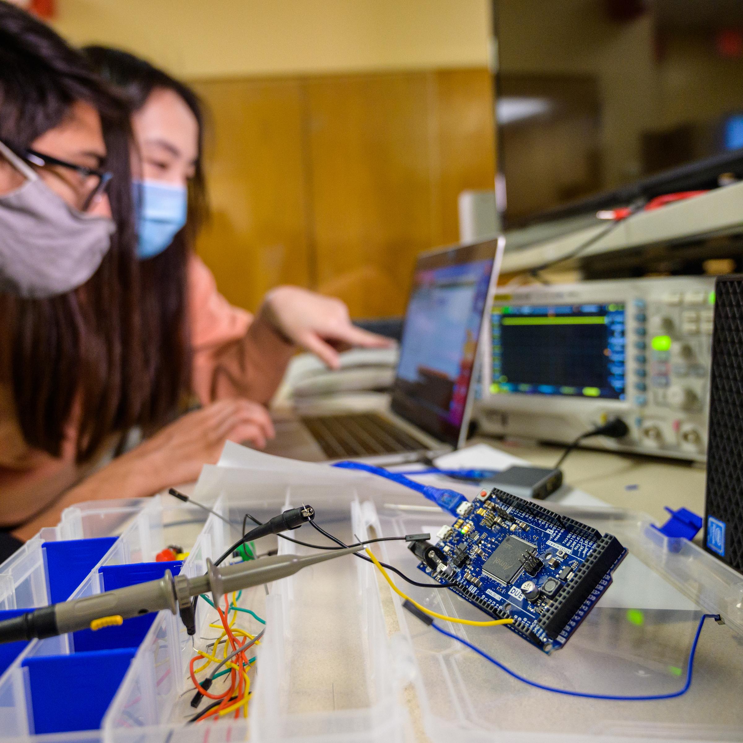 two students working on a project and looking at a laptop