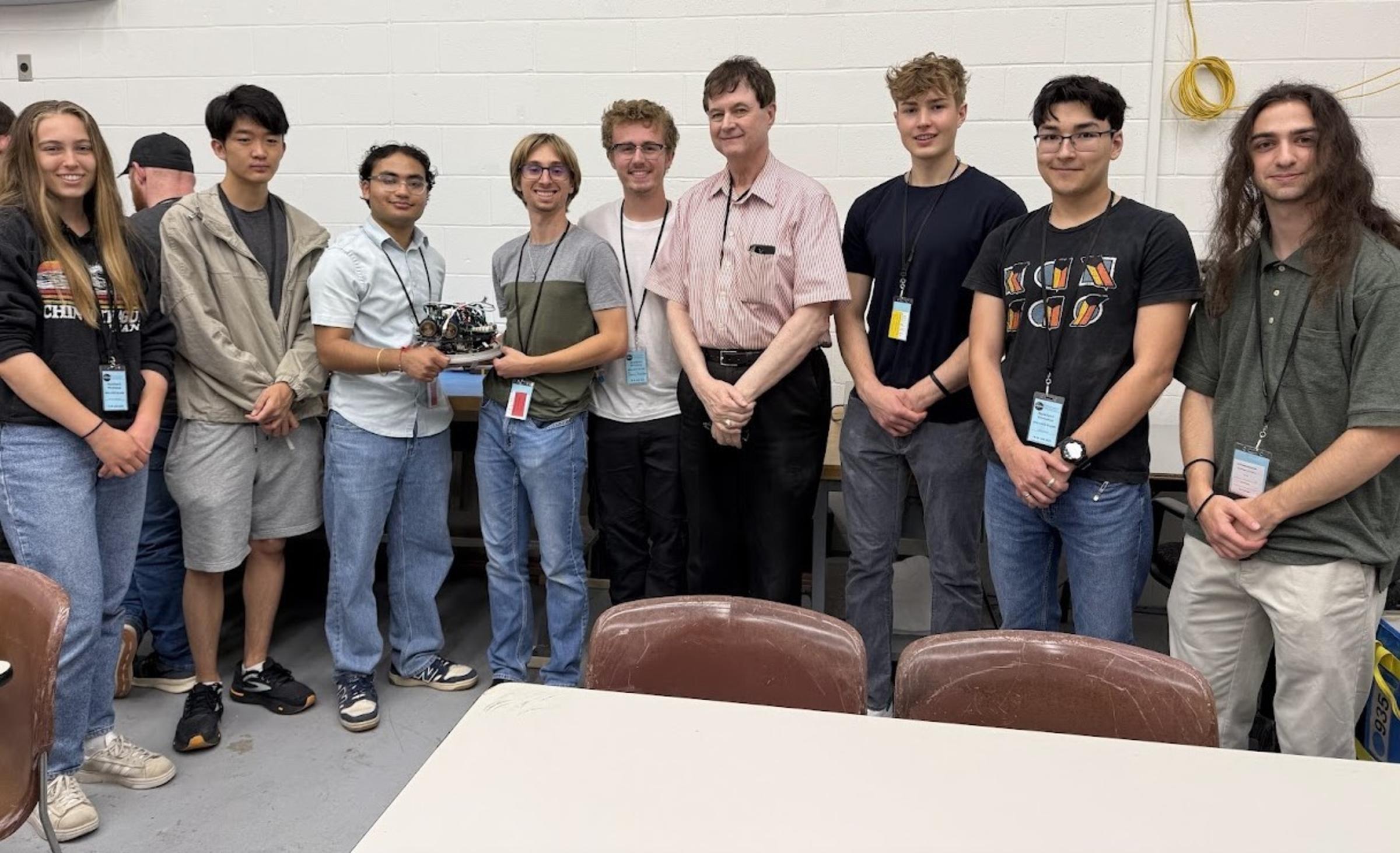 A group of 9 Stevens students stand in a semicircle looking at the camera.
