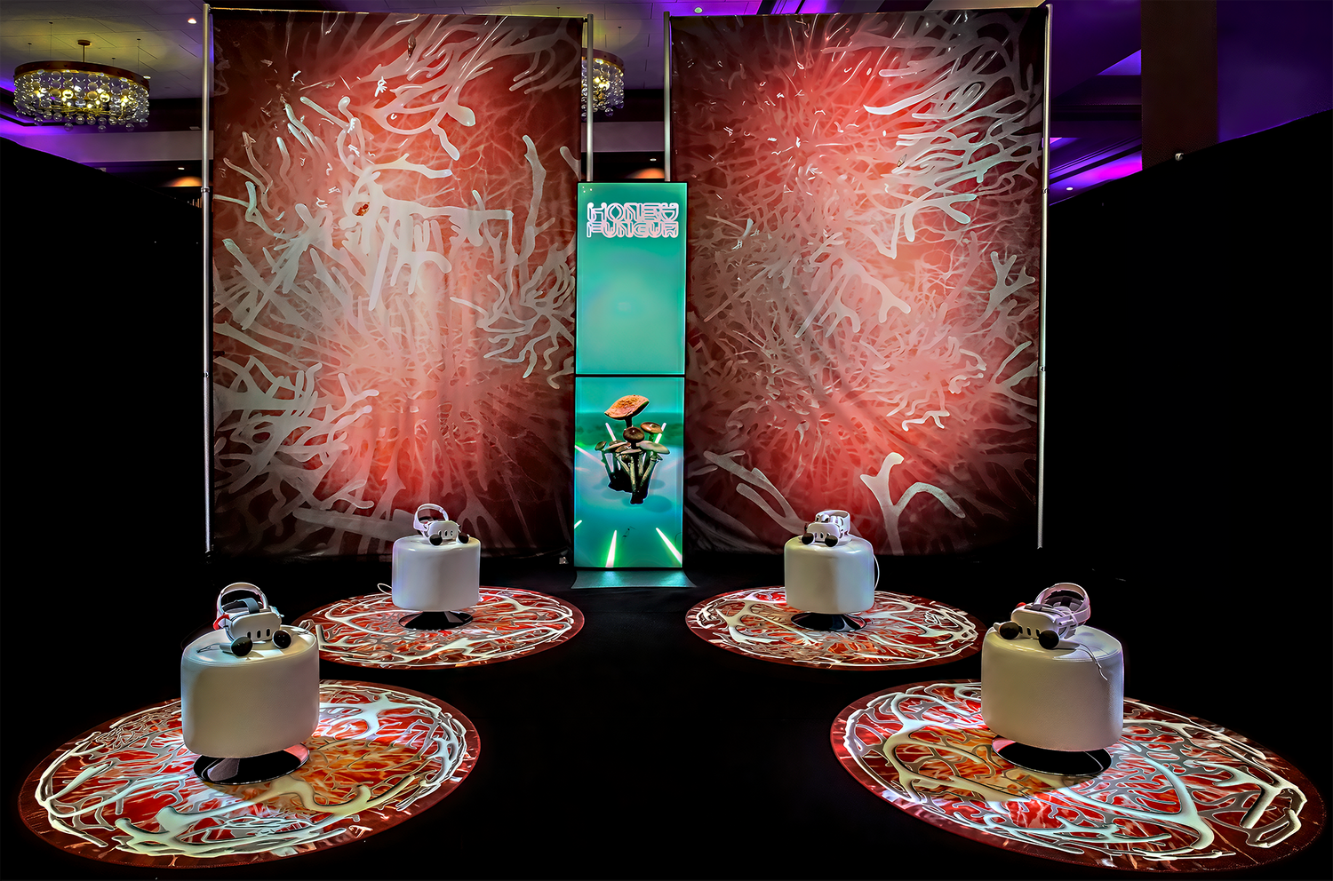 Photo showing Jonah's King's virtual reality project "Honey Fungus" at SXSW. Shows four stations and three backdrops, all stylized with red fungus imagery.