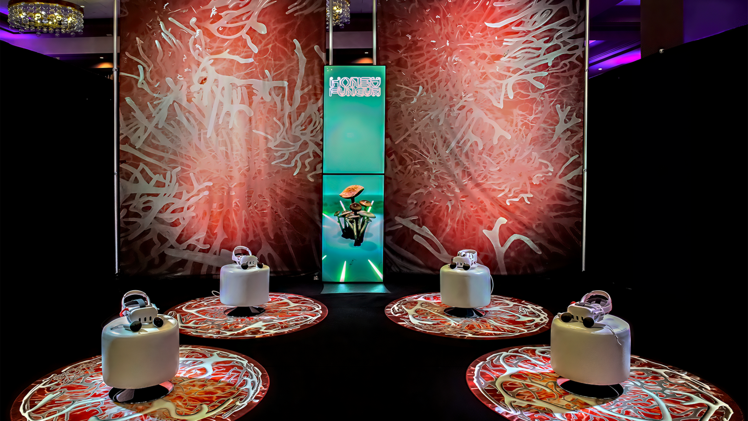 Photo showing Jonah's King's virtual reality project "Honey Fungus" at SXSW. Shows four stations and three backdrops, all stylized with red fungus imagery.