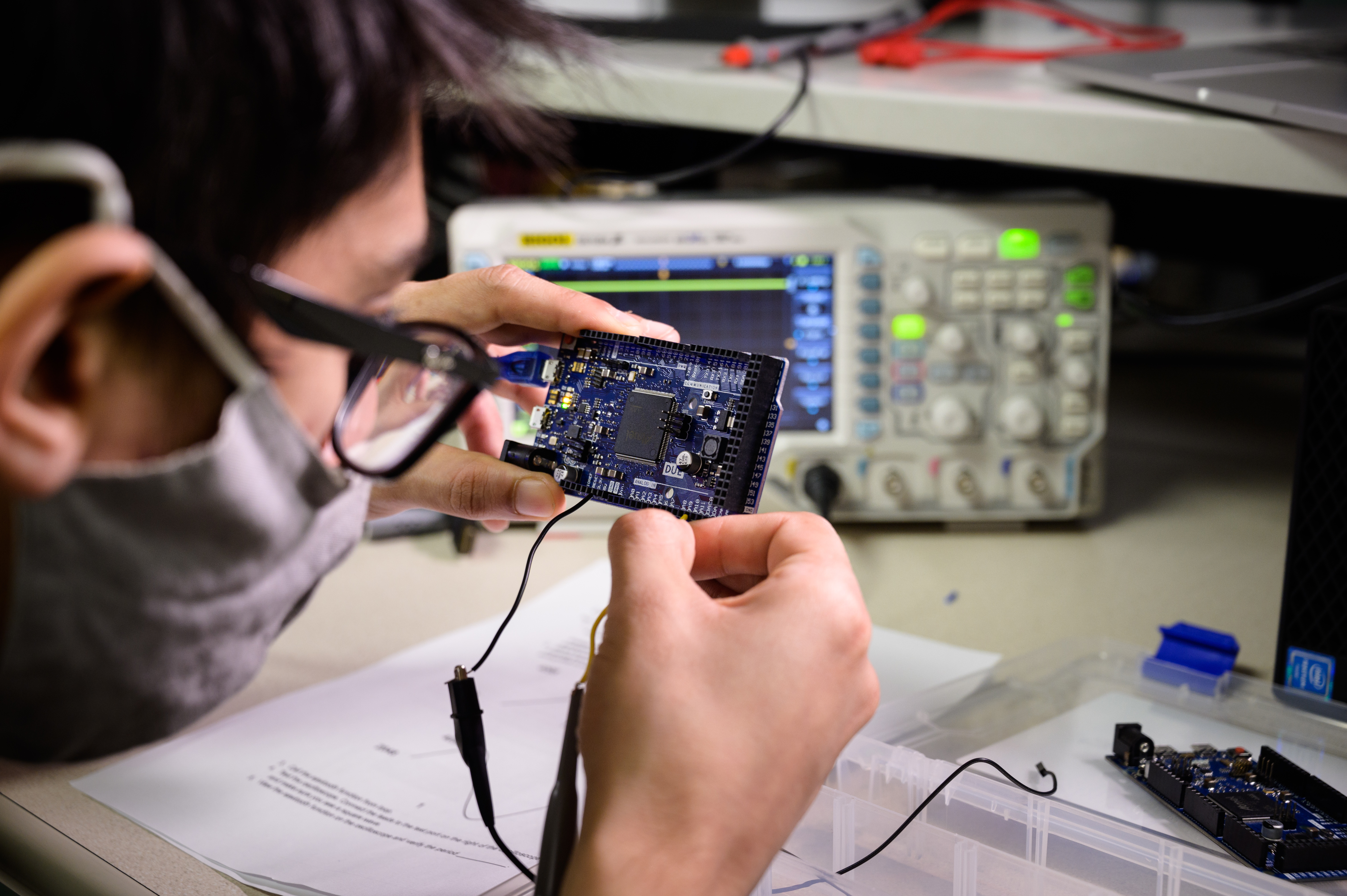 Student wearing glasses adjusts circuit board