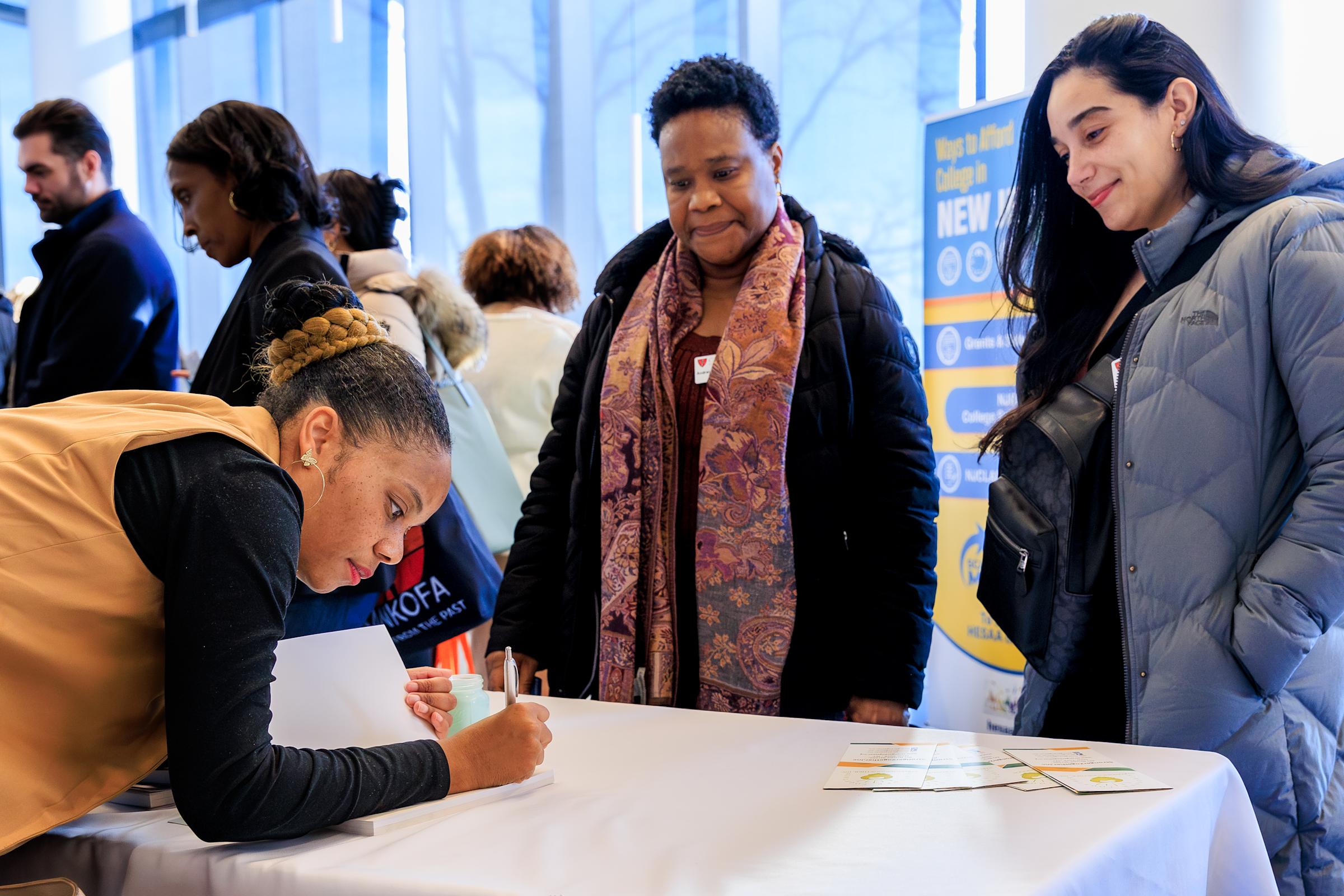 Three women interact at a table at the Resource Fair