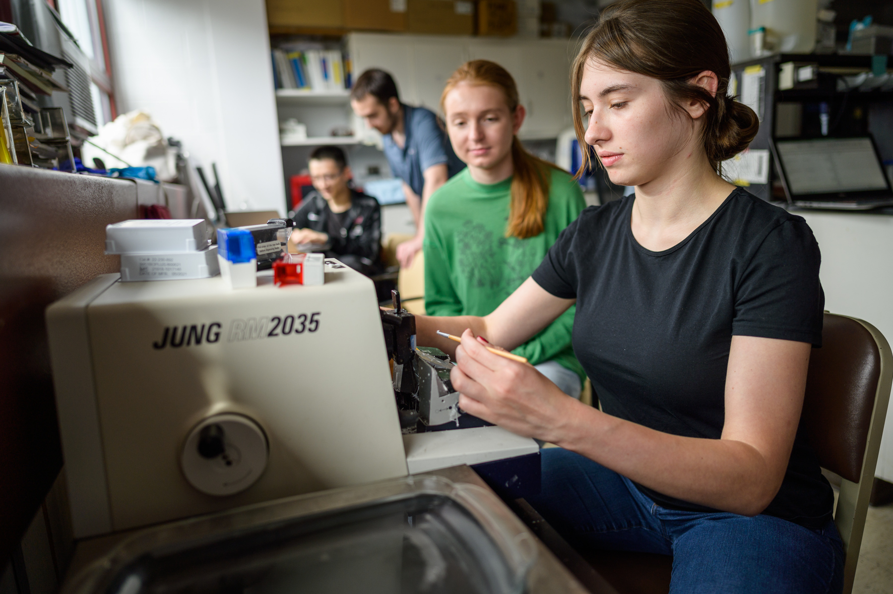 Two female students work at a machine.