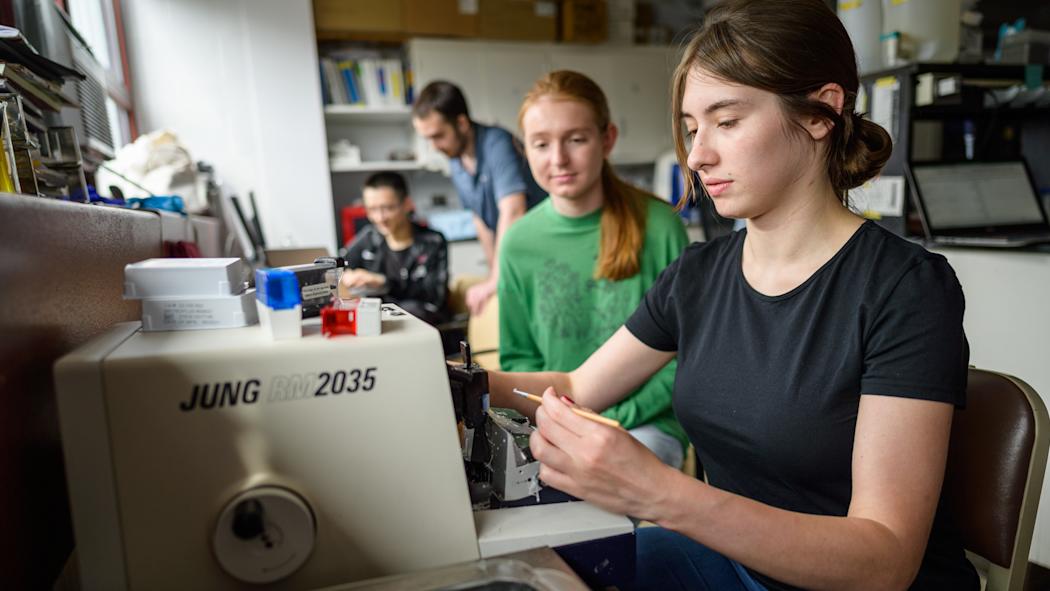 Two female students work at a machine.
