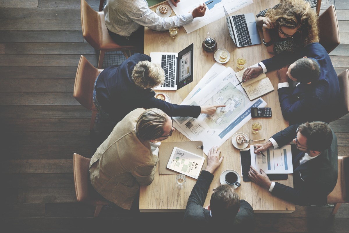 Stock of Individuals working at table with laptops and plans 