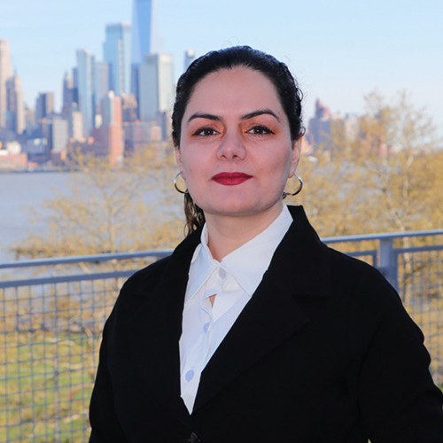Headshot of Zahra Shoorvazi in professional business attire with the lower Manhattan skyline in the background