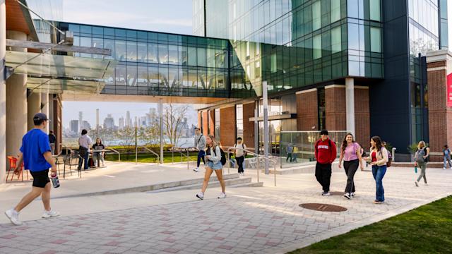Students smile and walk in front of the South Tower at the UCC
