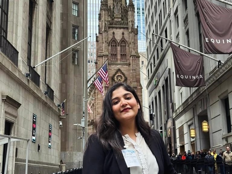 Kaushal Makadia stands on the street in New York City with the spire of a building in the background.