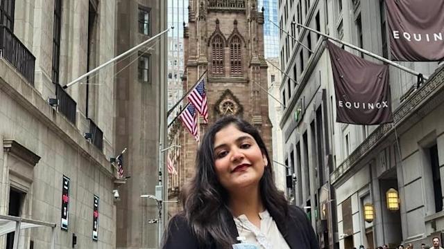 Kaushal Makadia stands on the street in New York City with the spire of a building in the background.