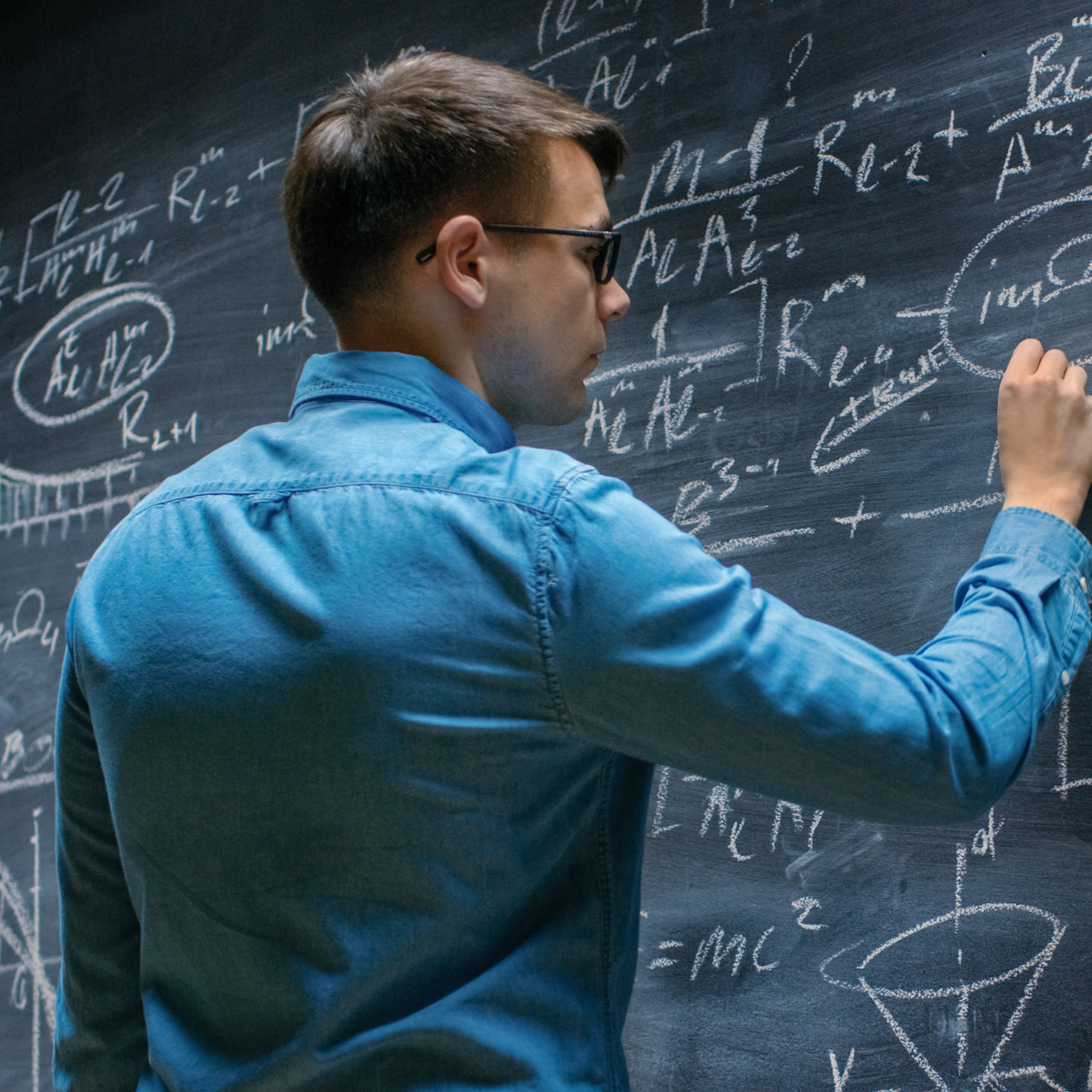 mathematician at chalk board writing equations