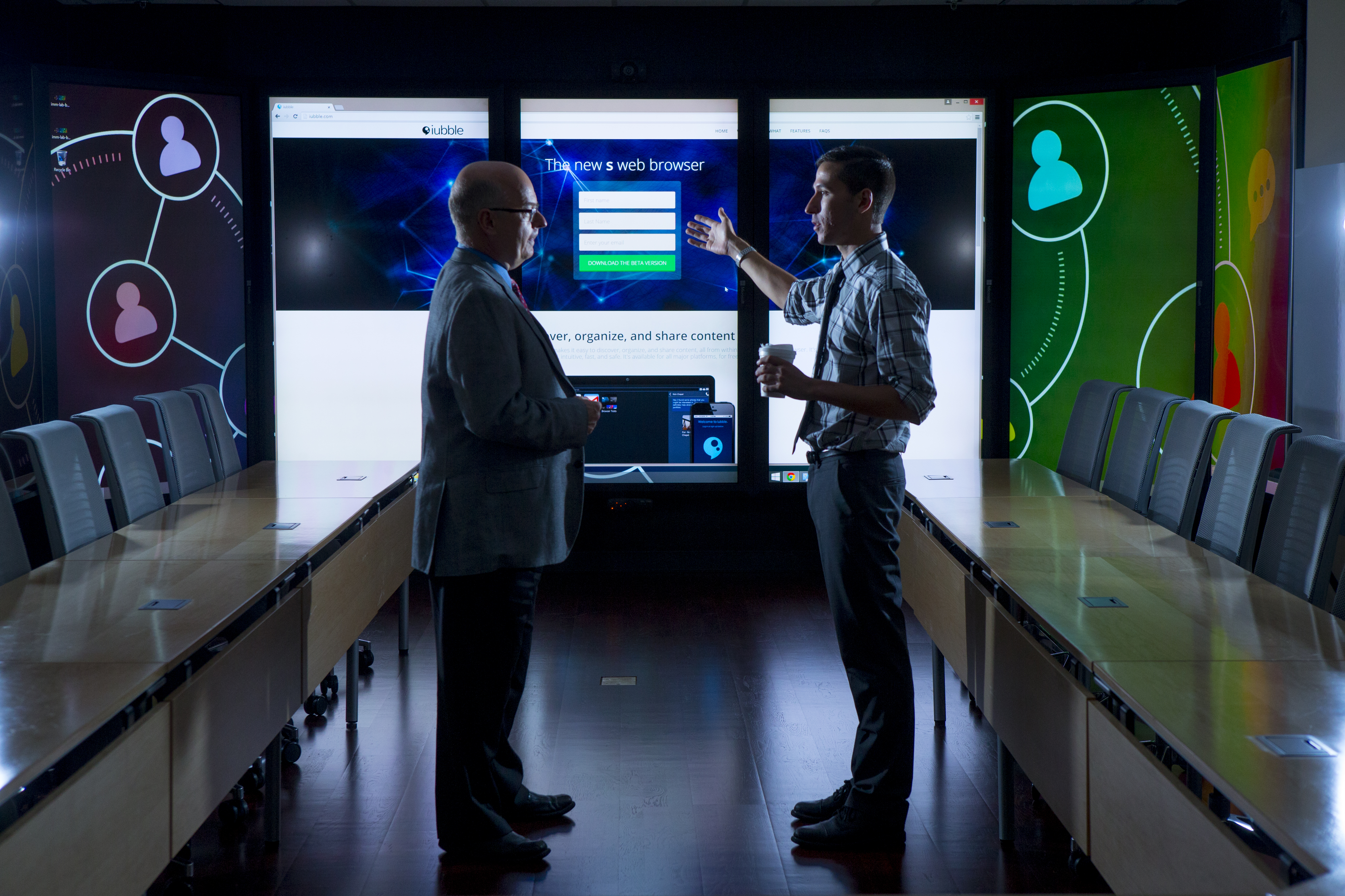 A faculty and a student talking in the immersion lab surrounded by screens