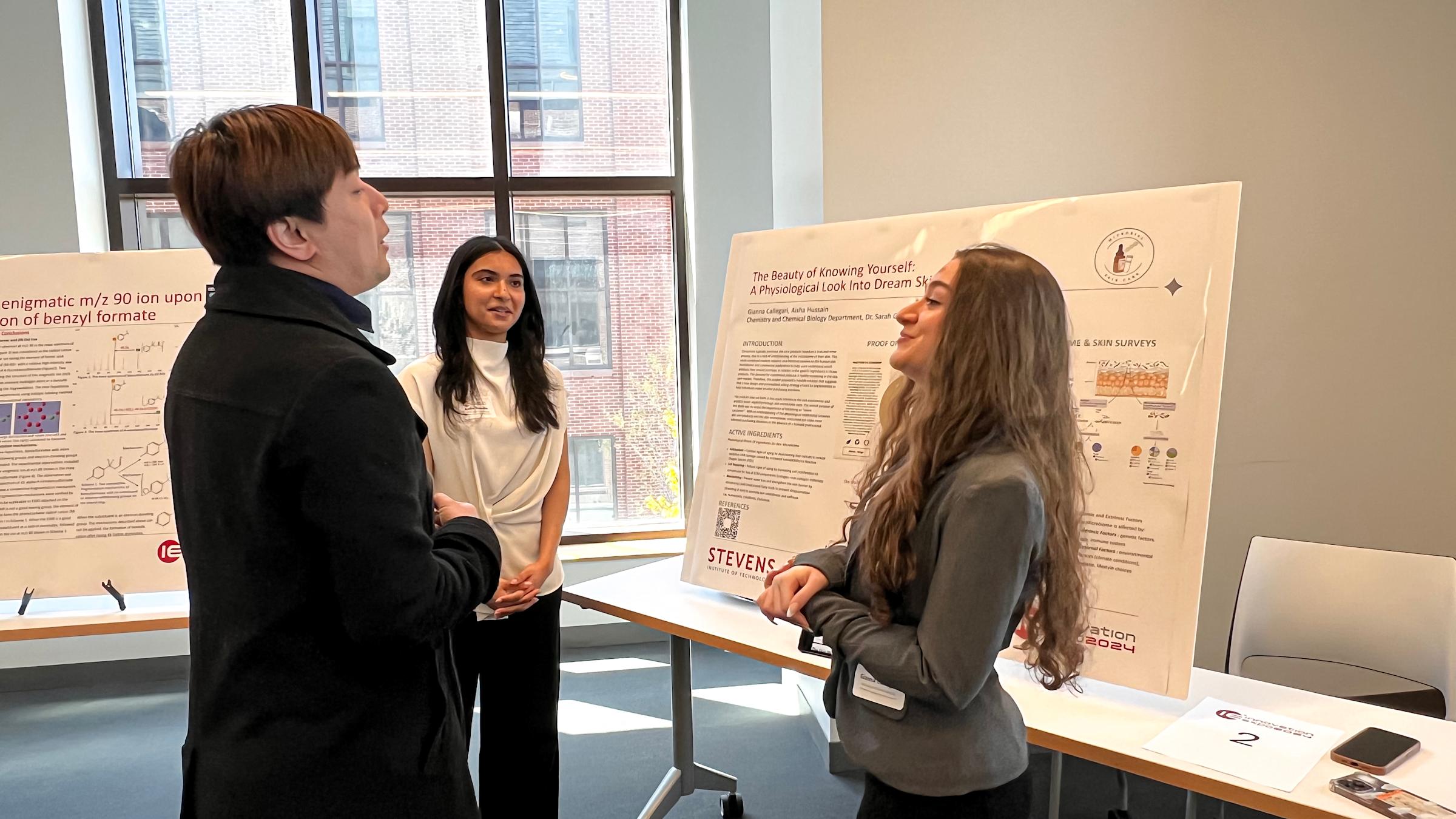 Students network among posters displaying presentations on poster boards.