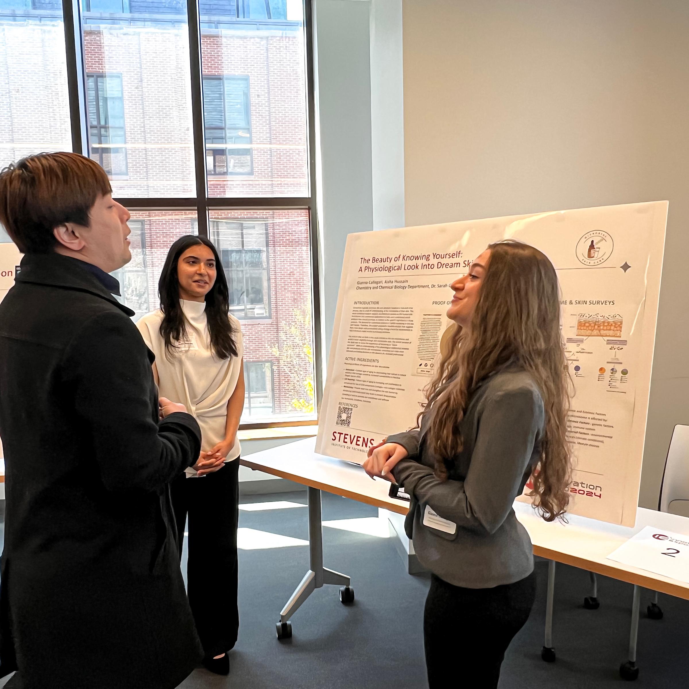 Students network among posters displaying presentations on poster boards.