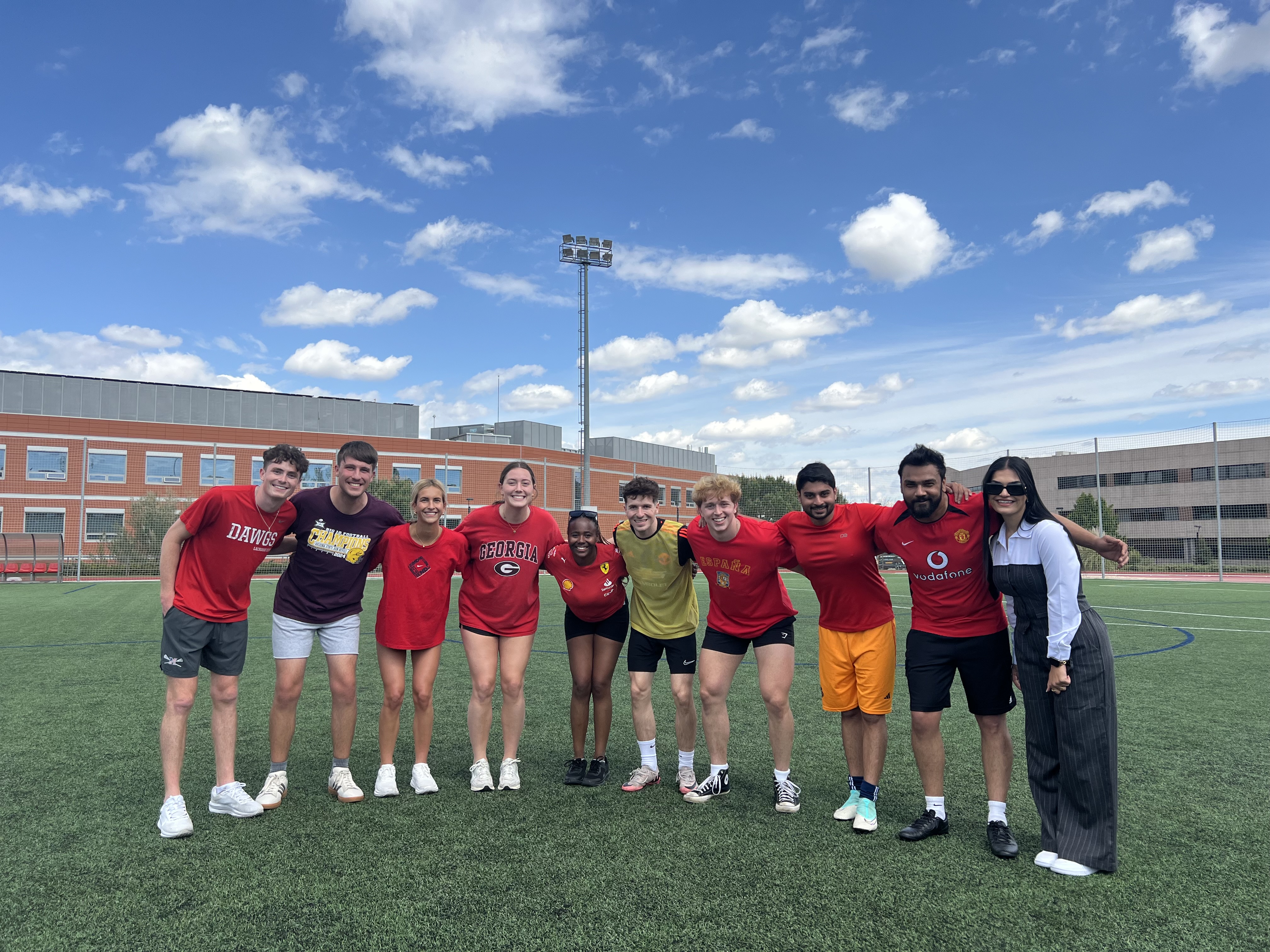 Bupe Bwalya stands in the middle of a group of students on a soccer field.