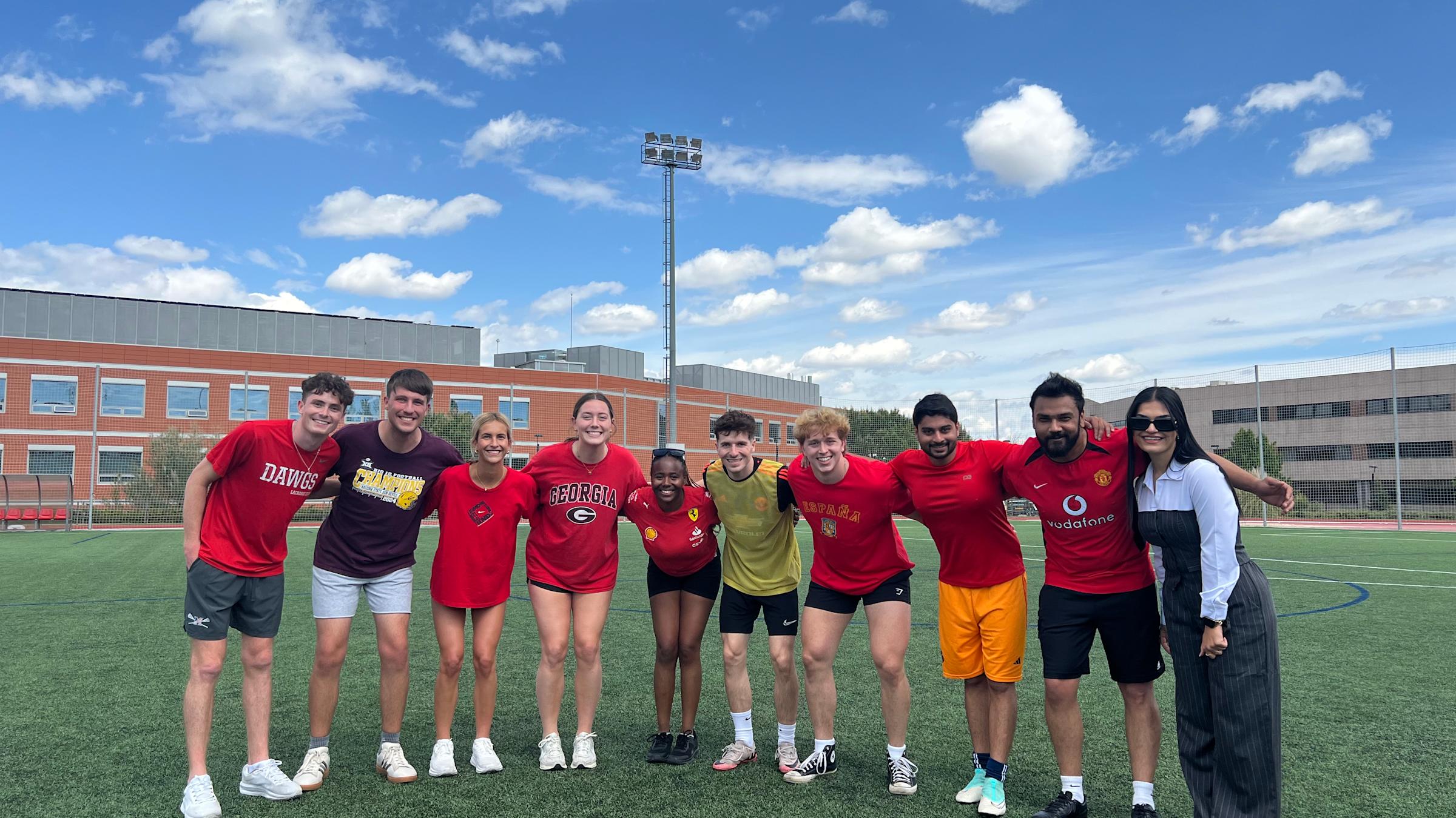 Bupe Bwalya stands in the middle of a group of students on a soccer field.