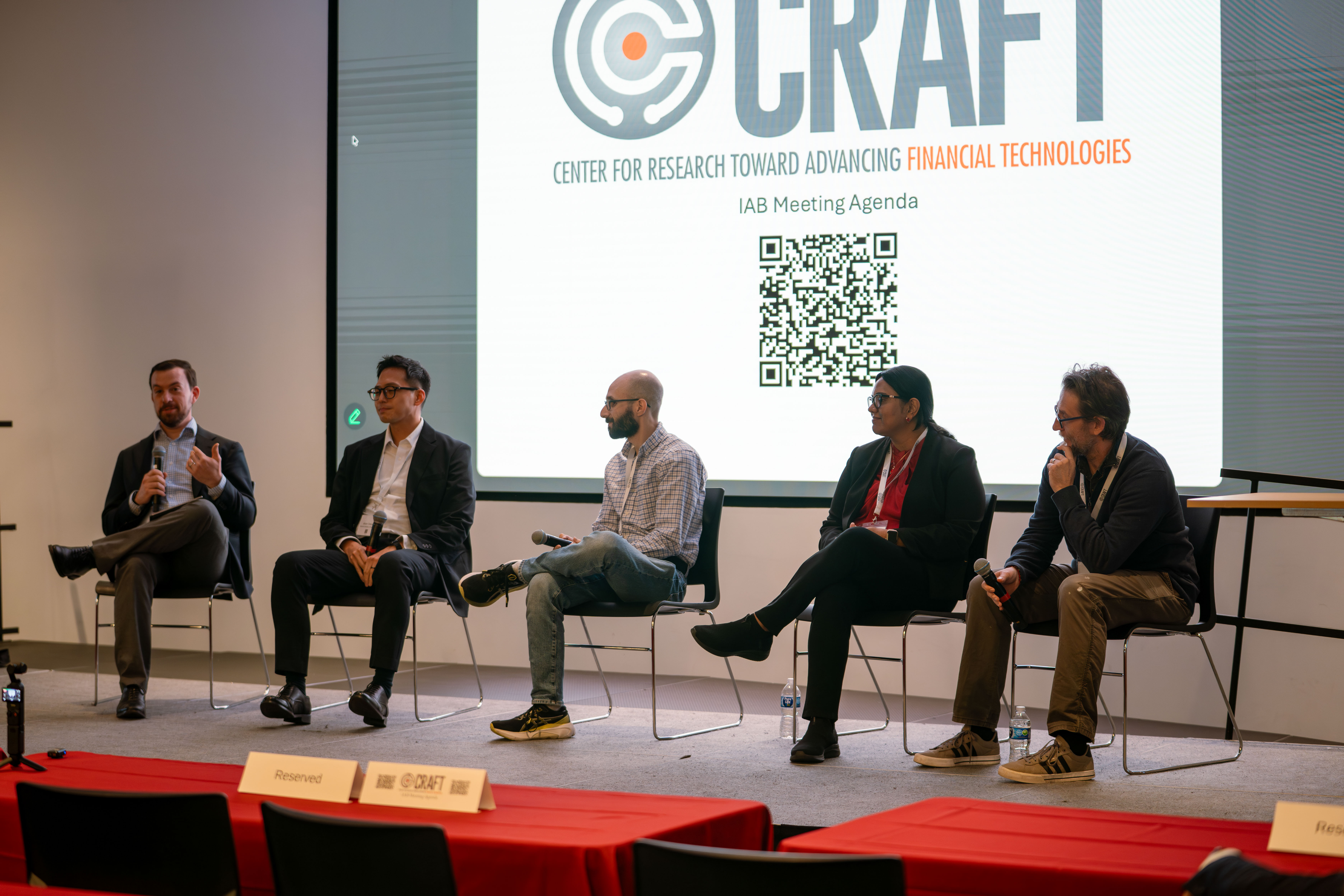 Five panelists sit on an elevated stage to discuss new fintech trends. 