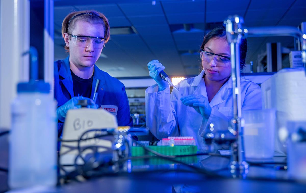 A male and female student wearing personal protective gear working in the newly renovated chemical biology laboratory.