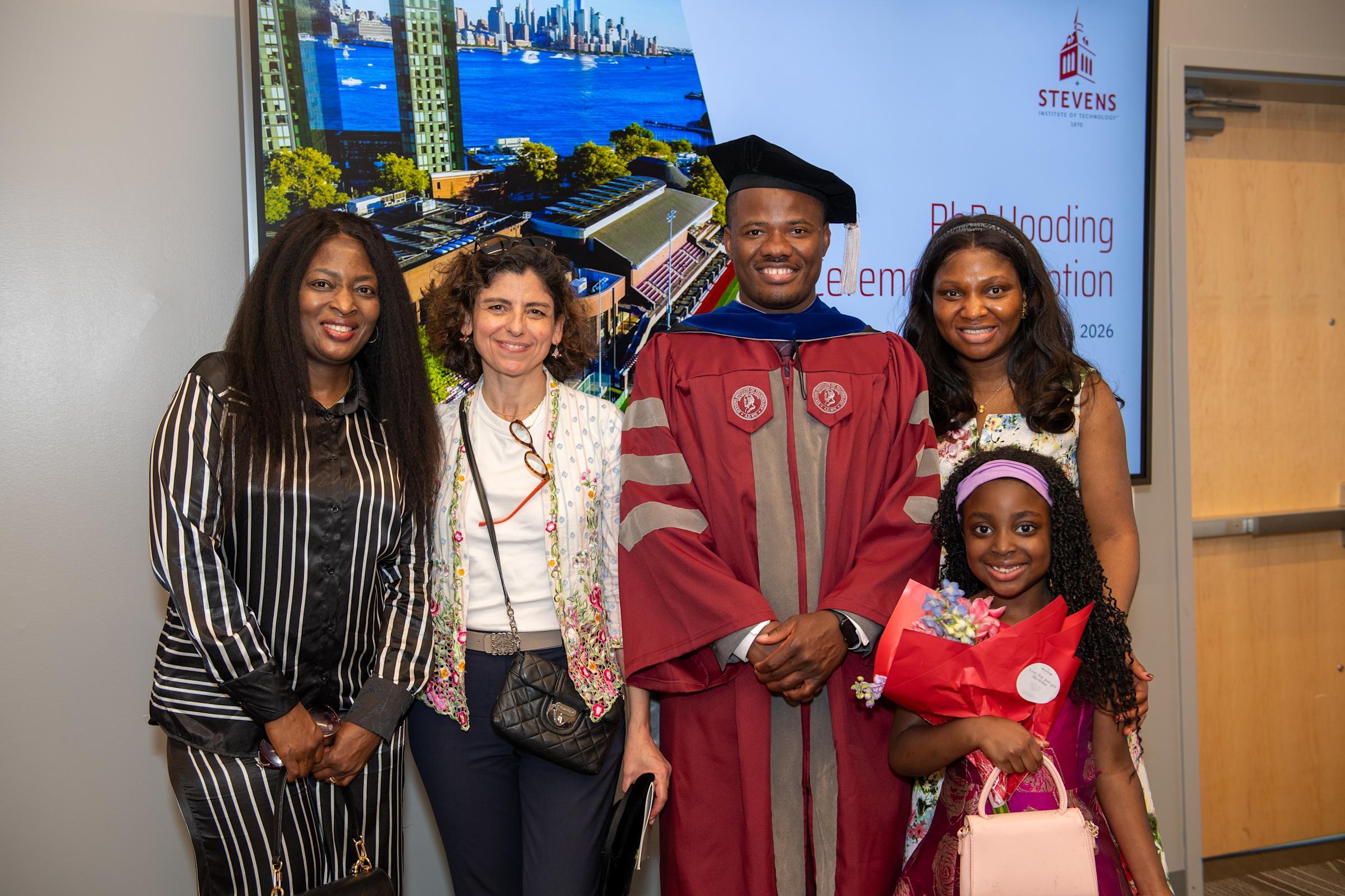 Christopher Mbonu pictured with his family and his advisor, Associate Professor Pinar Akcora, after the Ph.D. hooding ceremony.