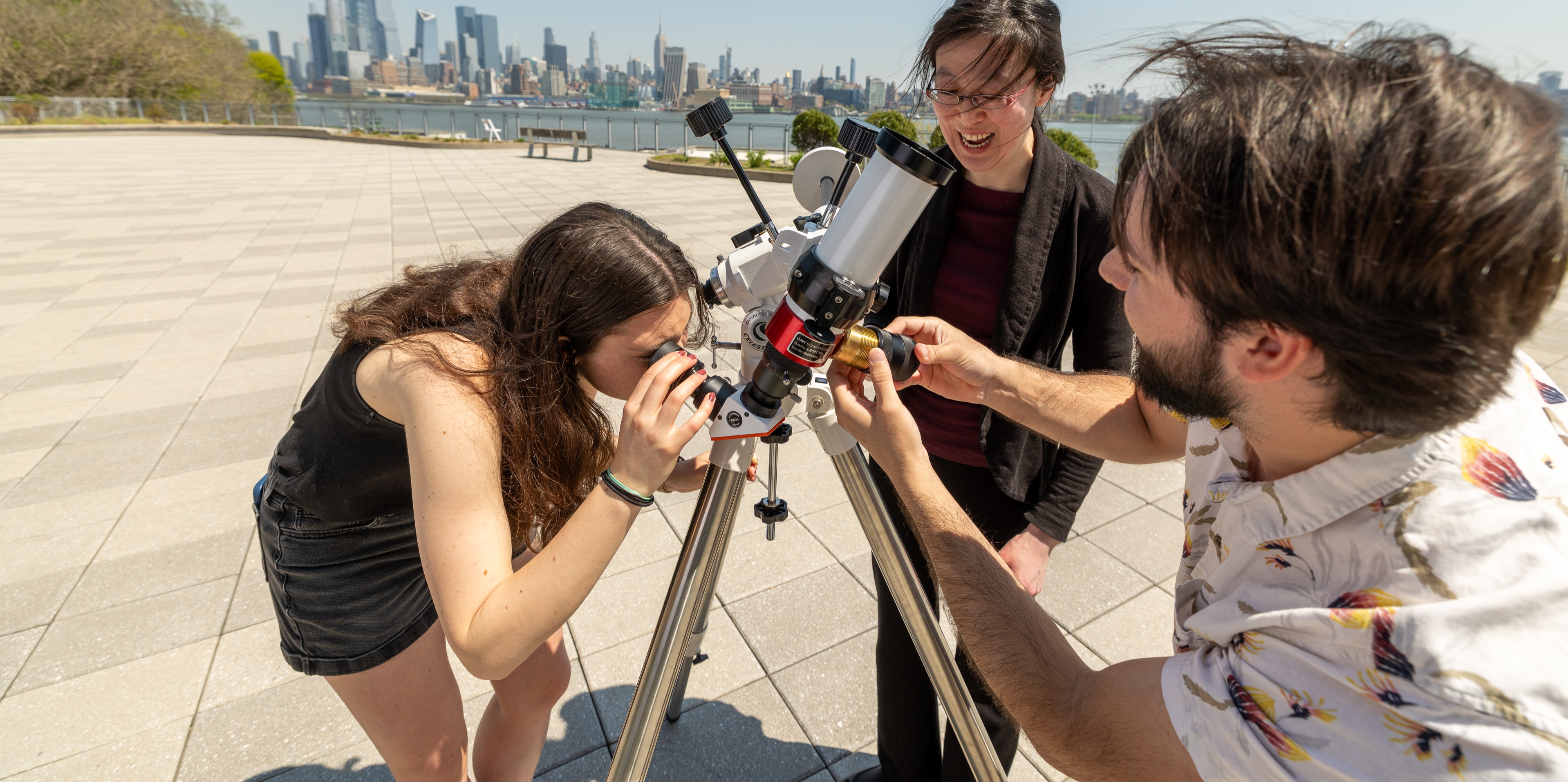 Professor Ting Lu and two students setting up a telescope on New York harbor.