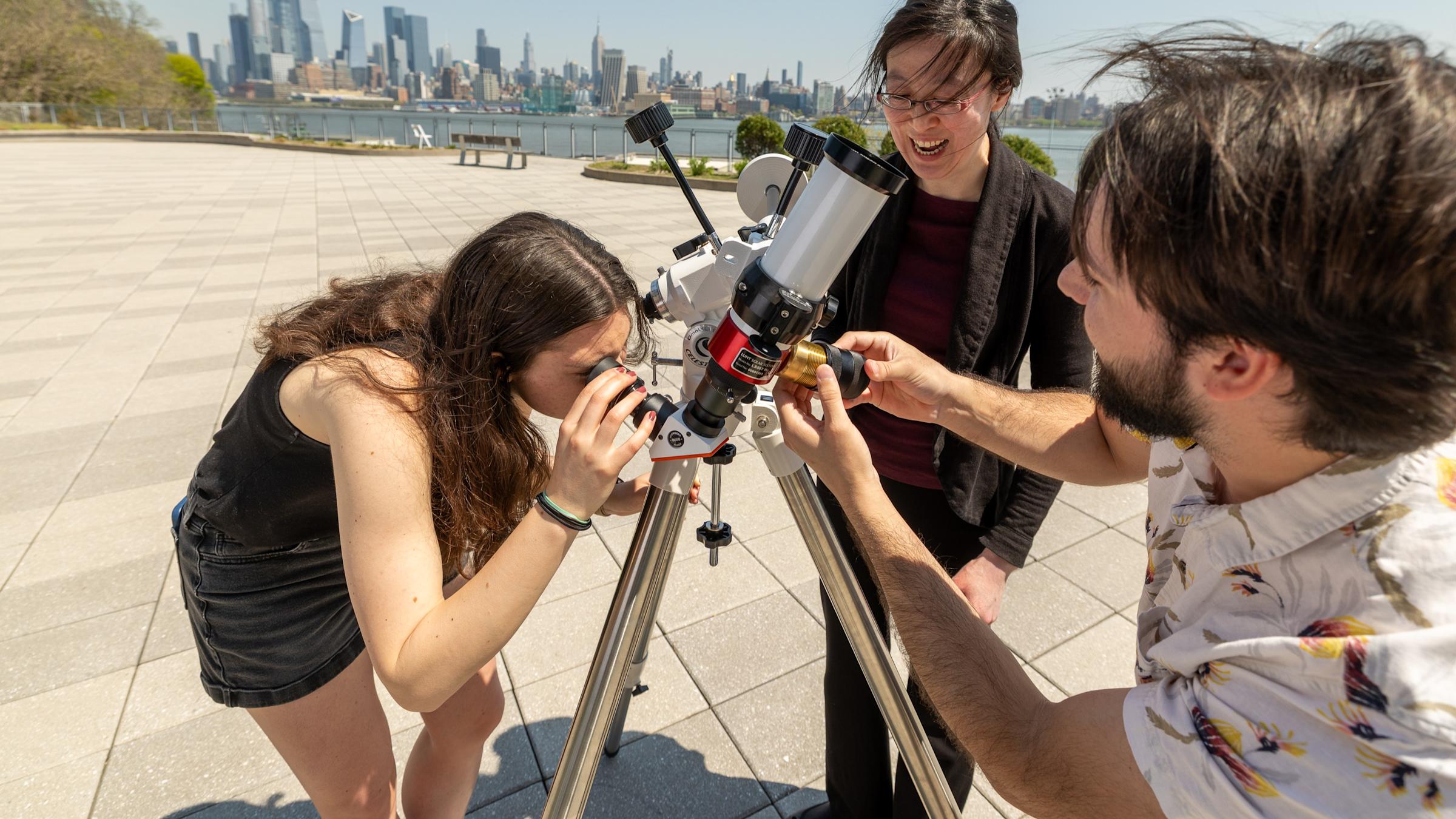 Professor Ting Lu and two students setting up a telescope on New York harbor.