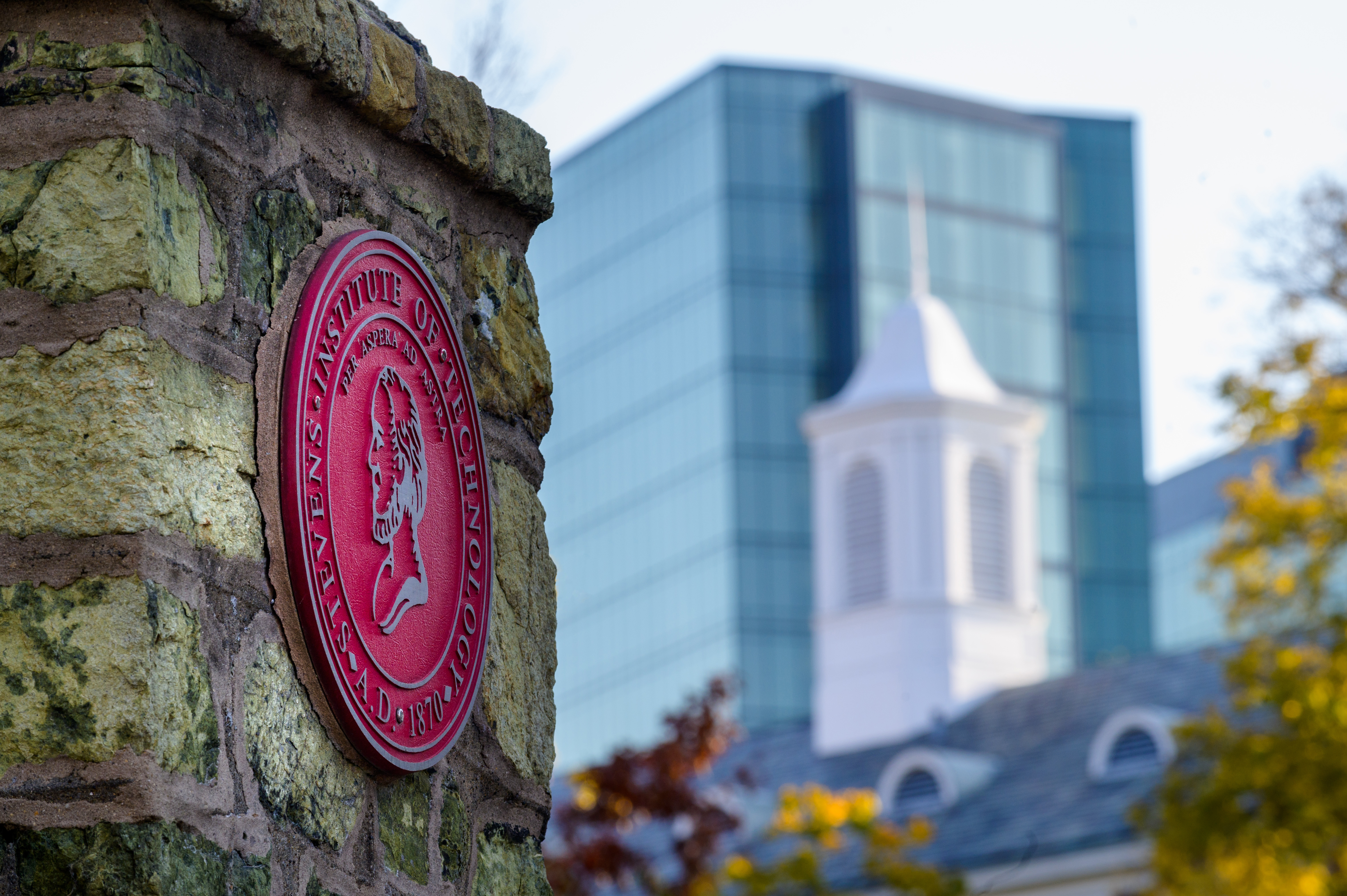 Stevens seal on gateway in foreground with buildings in background.