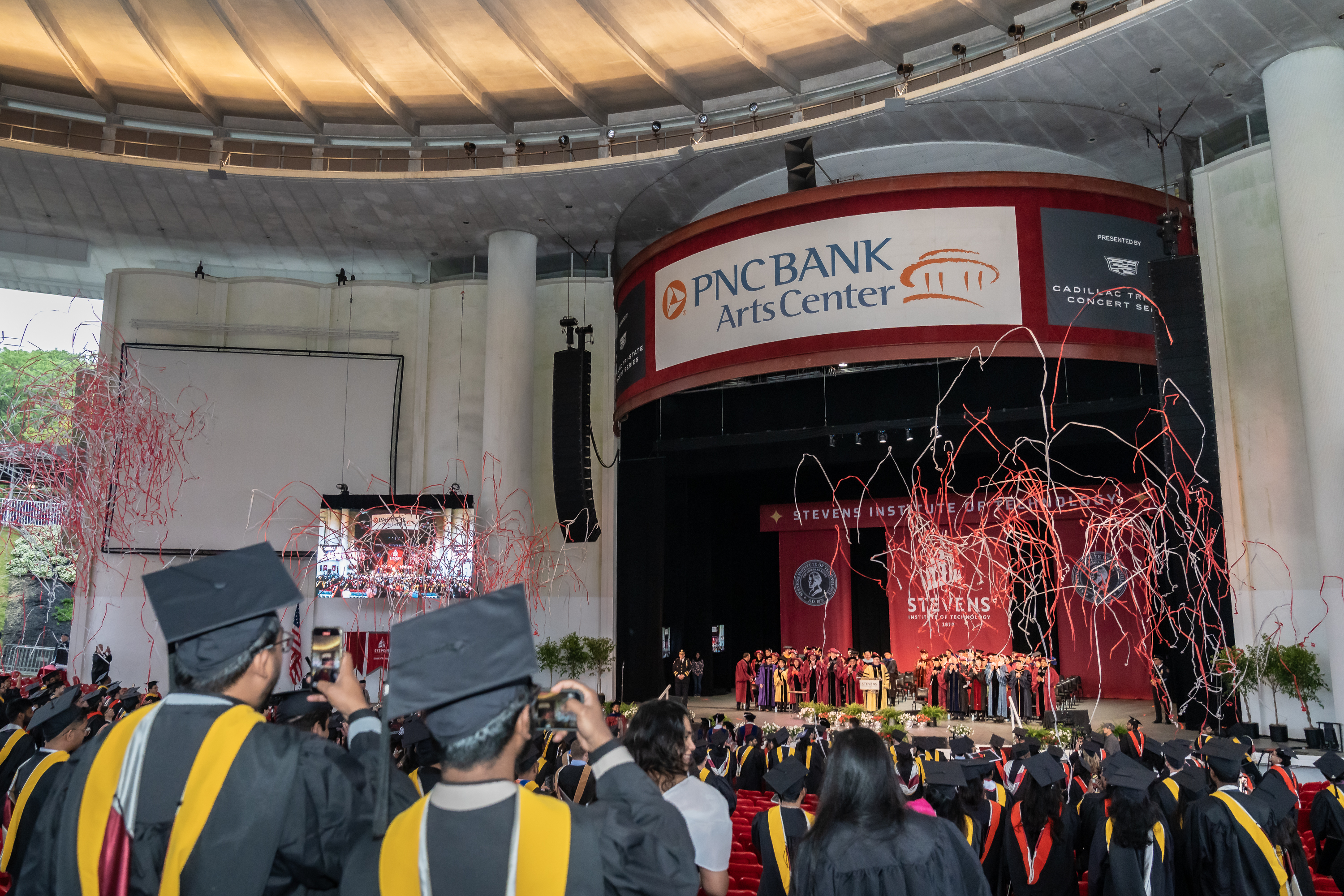 Students celebrate commencement as streamers shoot into the air. 