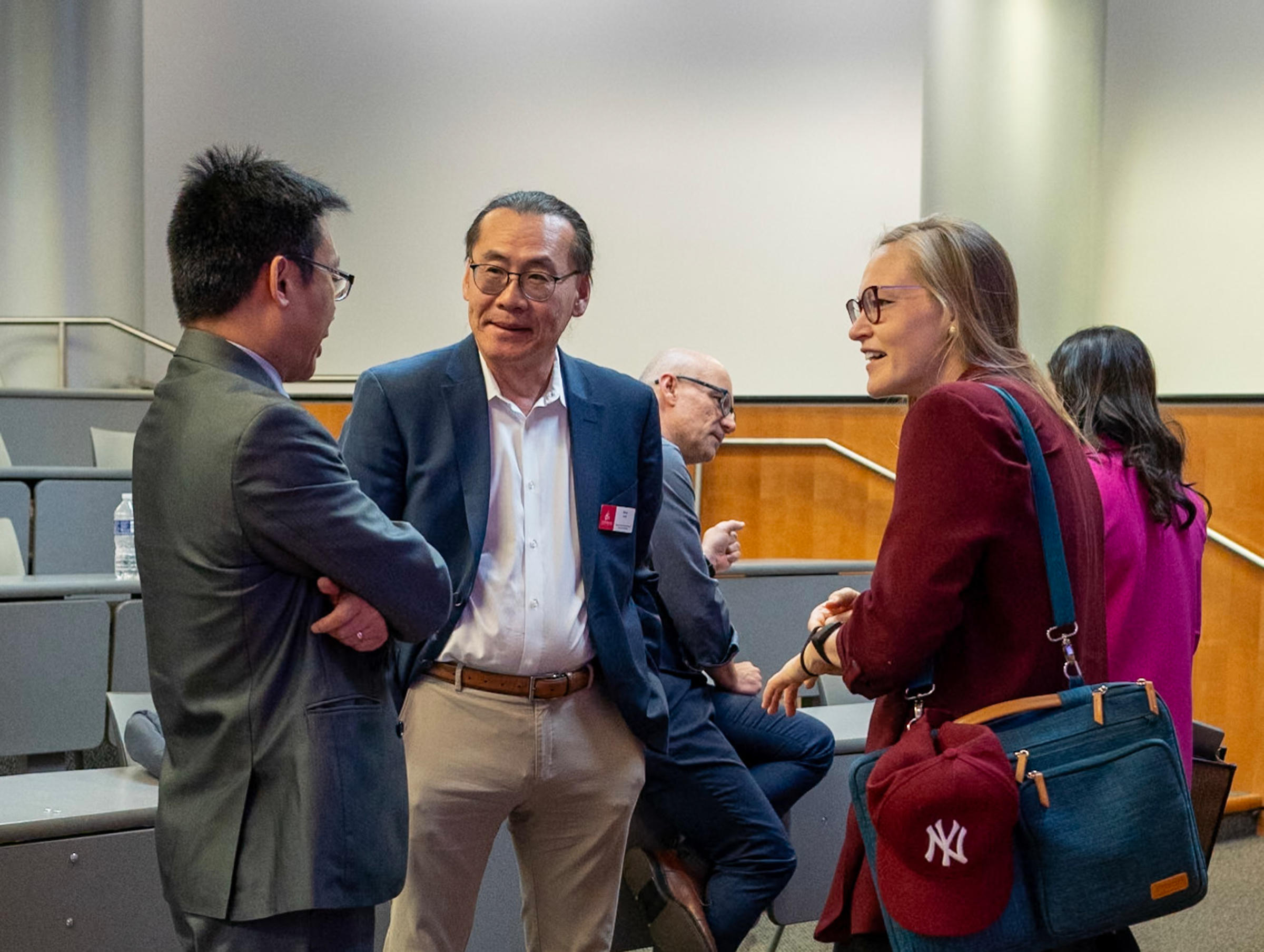 Woo Lee stands in between a man and a woman having a conversation.