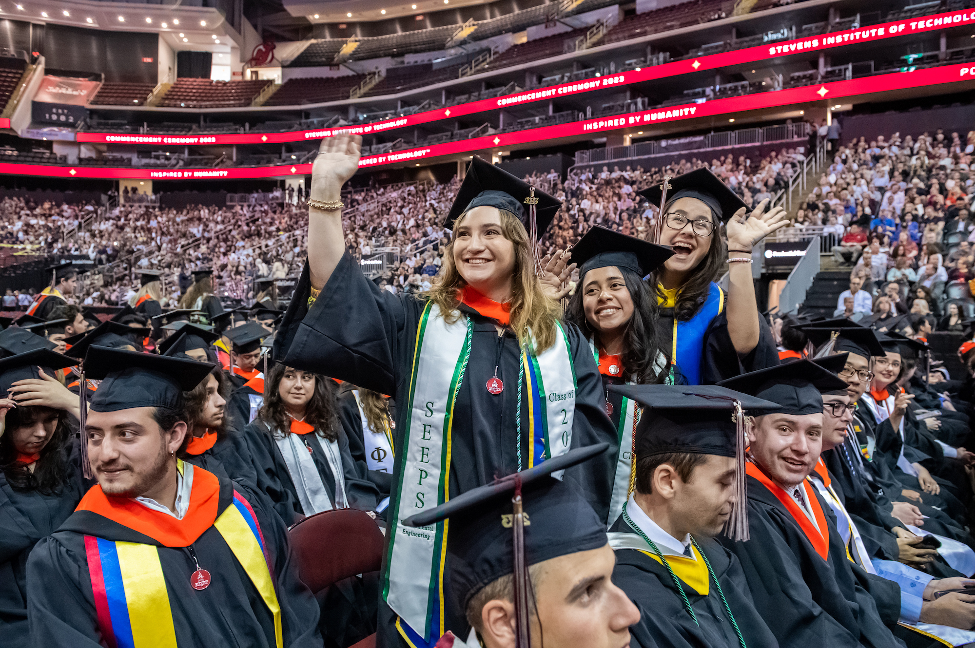 Graduates standing and waving to the crowd at the 2023 Commencement ceremony