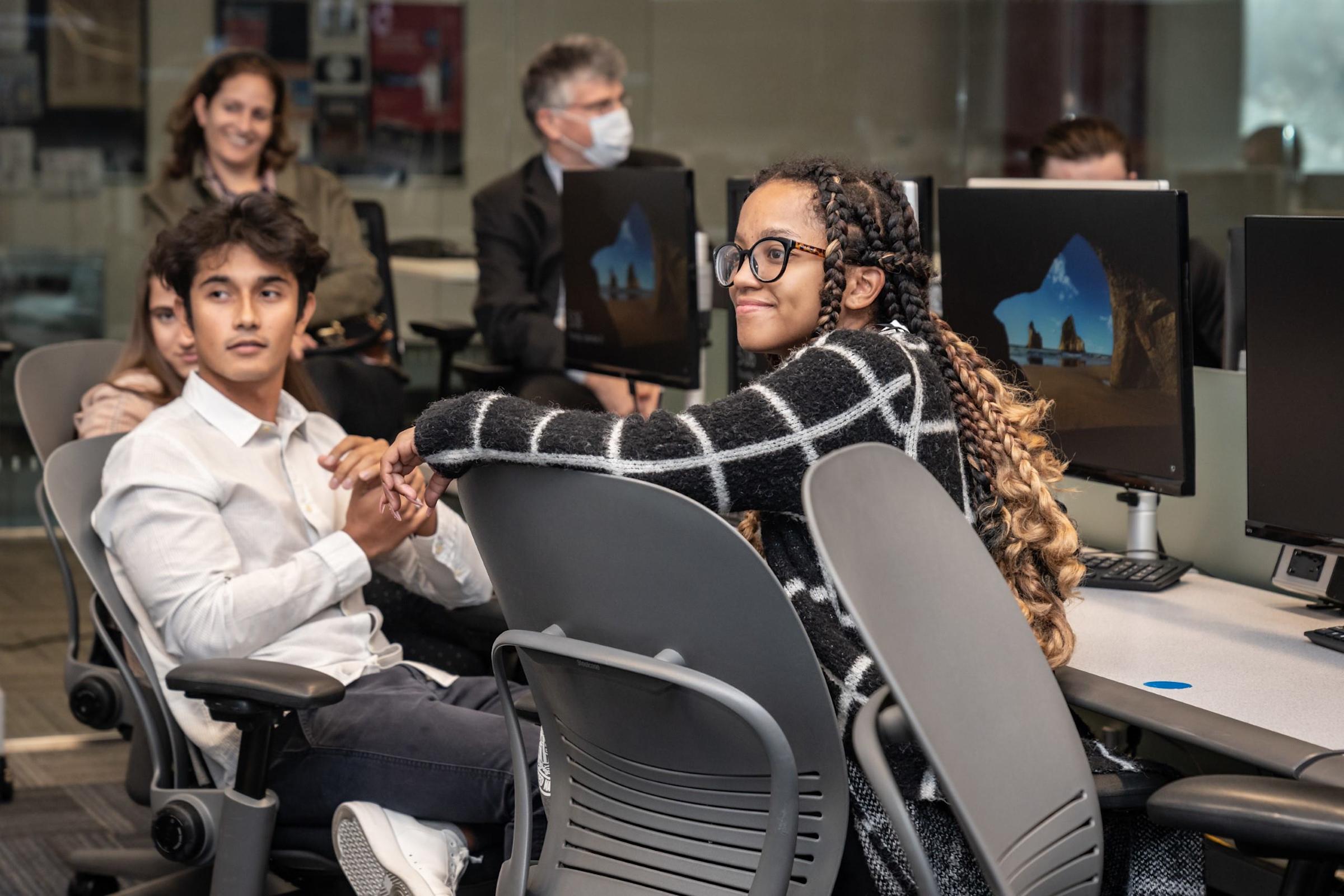 Several students are at computers listening to a presentation at Stevens
