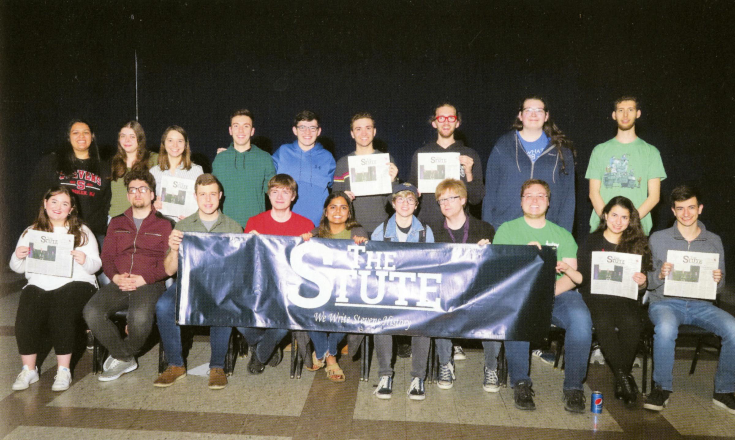 Group of Stute editors sitting with a Stute banner.